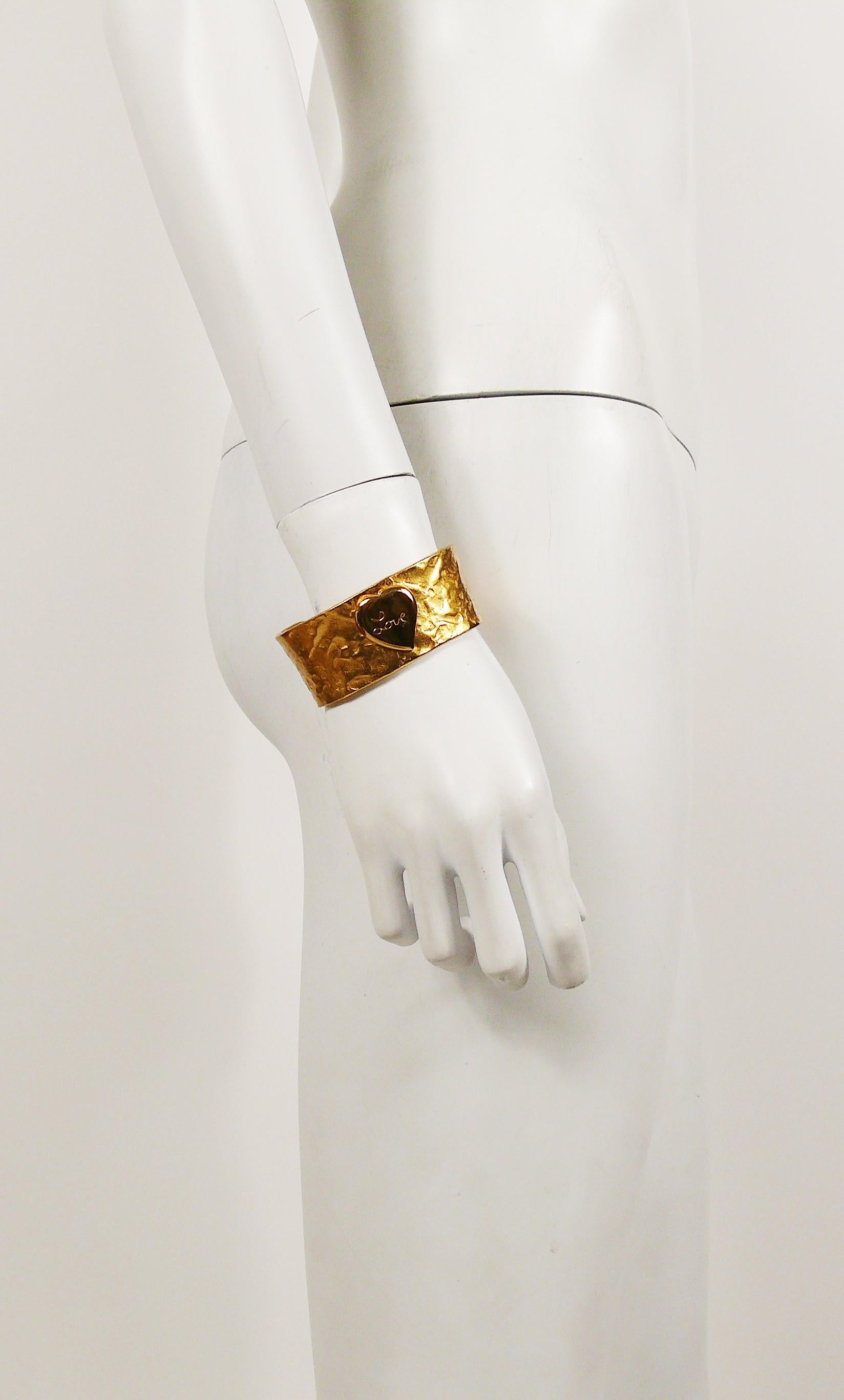 YVES SAINT LAURENT vintage hammered gilt cuff bracelet featuring a heart centrepiece with engraved LOVE.

Embossed YSL Made in France.

Indicative measurements : inner max. width approx. 6.4 cm (2.52 inches) / height approx. 2.8 cm (1.10