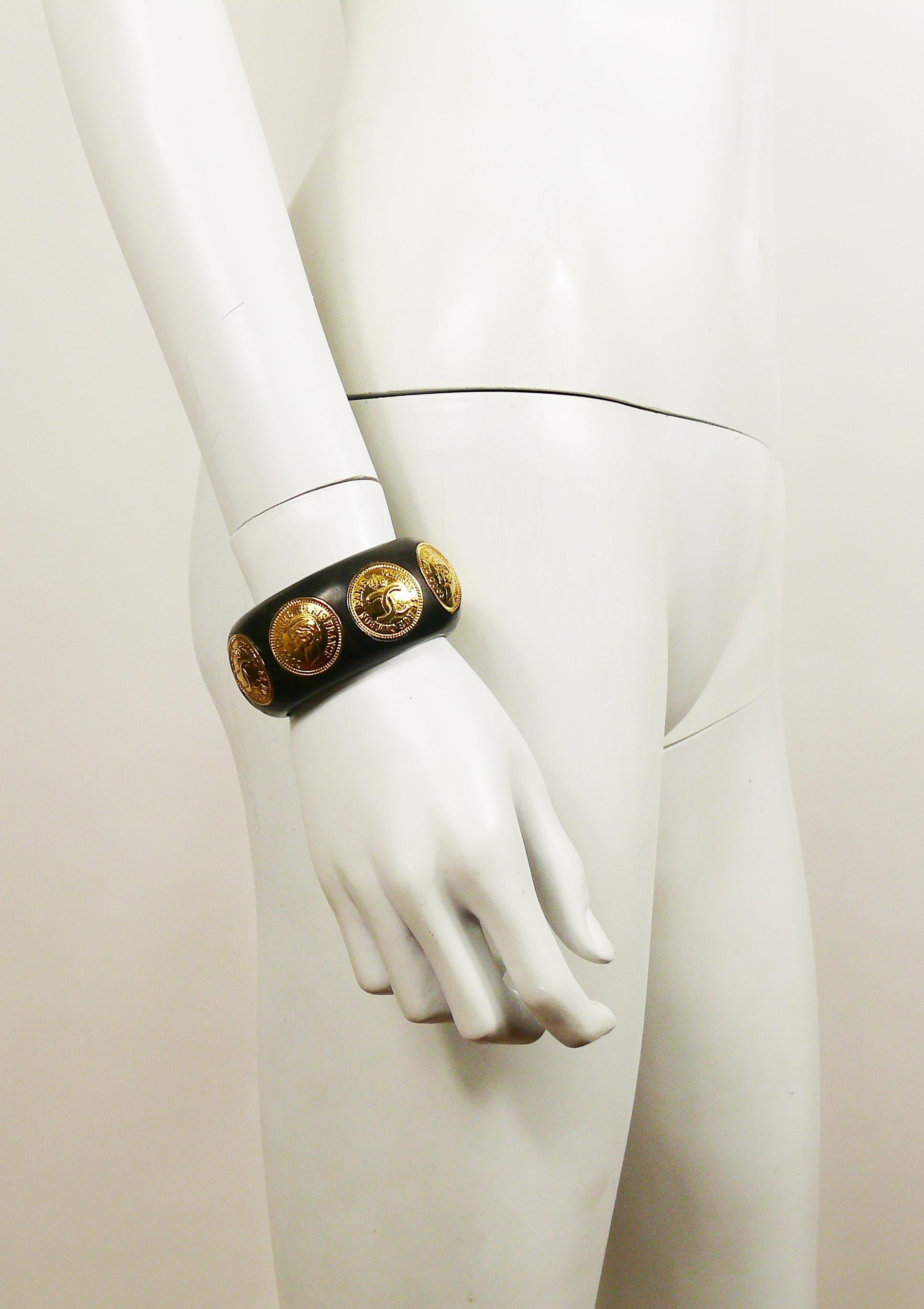 CHANEL vintage 1993 iconic and rare wooden cuff bracelet featuring gold toned coins with COCO profile alterning with crowned CC 31 RUE CAMBON PARIS.

Season 28 (1993).

Embossed CHANEL 2 8 Made in France.

Indicative measurements : inner