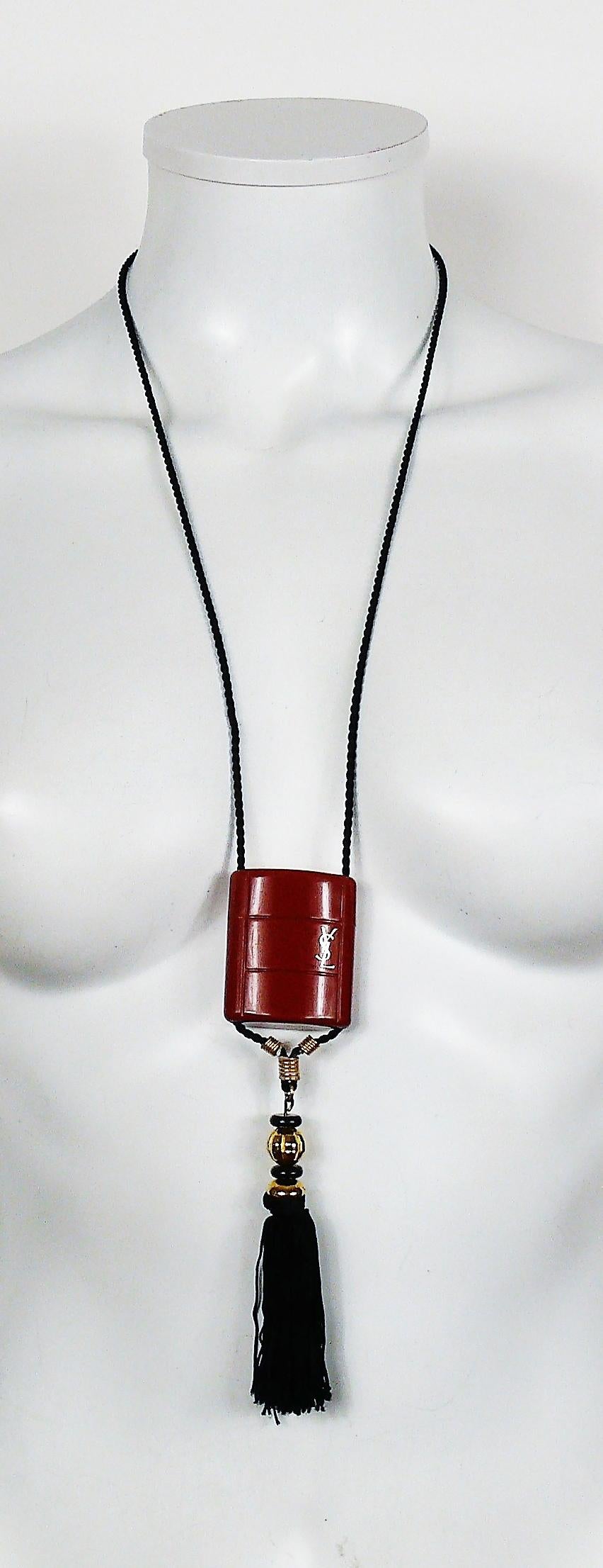 YVES SAINT LAURENT vintage OPIUM inro pendant necklace.

This necklace consists of a black cord, a burnt orange plastic container, a silk tassel adorned with black and gold tone beads.

Plastic container opens to insert a miniature bottle (no bottle