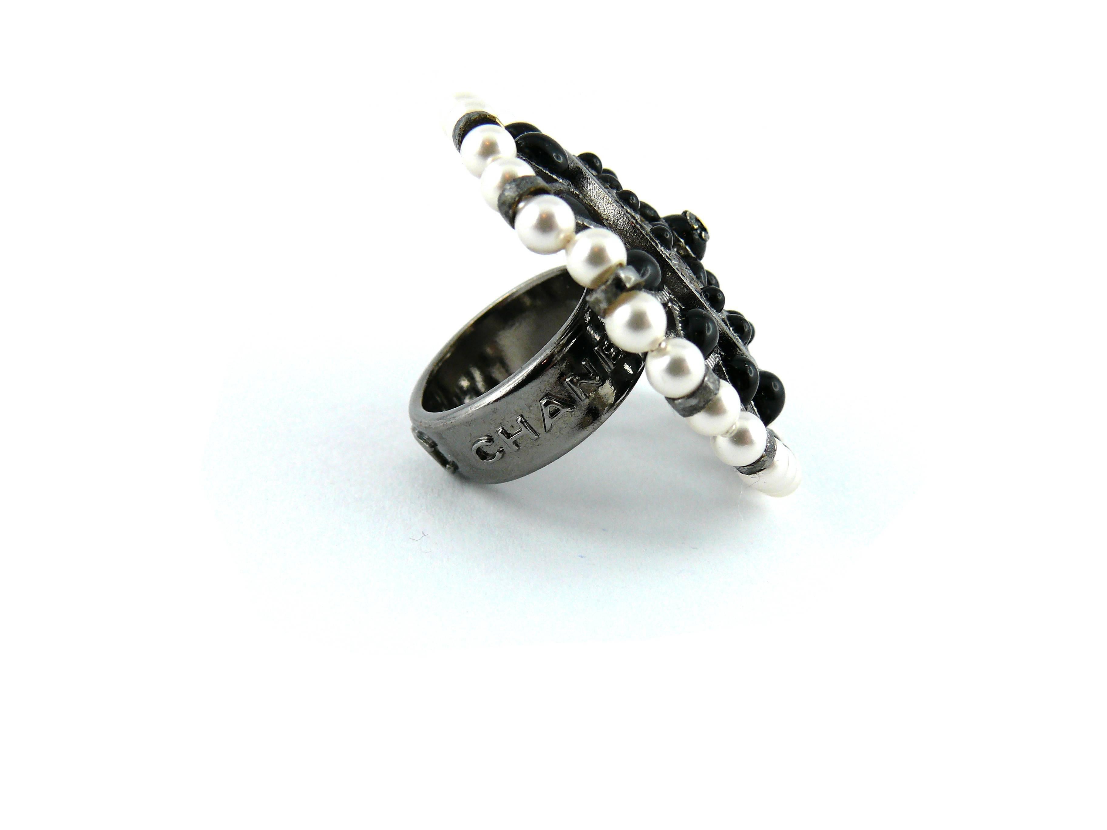 CHANEL massive black and white couture flower ring made of faux pearls and poured glass cabochons in a silver tone openwork setting.  Adorned with CC logo on the central cabochon.

Embossed Chanel Paris.

Size : US 6 3/4 - FR 54. 
Diameter of
