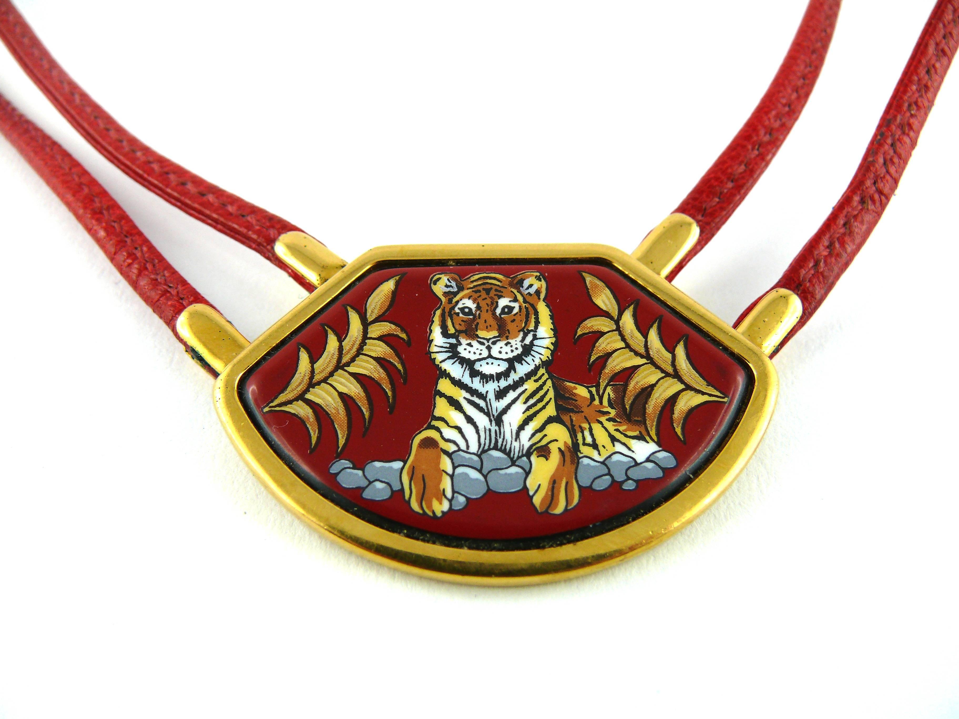 HERMES vintage rare Tigre Royal red leather and enamel choker necklace.

Gold plated metal with a multicolored enameled medallion featuring a sitting Tiger between two palm fronds on a red background, leather straps with saddle stitch.

Lobster claw
