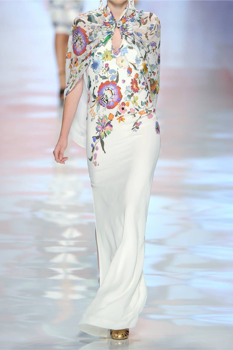 THIS ETRO GOWN MAKES A GRAND ENTRANCE UNFORGETTABLE WITH A COLORFUL BOTANICAL PRINT, SHARP SILHOUETTE, AND FLOWING CAPE.

ITALIAN SIZE 38

FLORAL-PRINT CREPE DE CHINE
RUCHED CAPE ATTACHES TO HALTER KEYHOLE NECKLINE, FALLS DOWN SHOULDERS AND