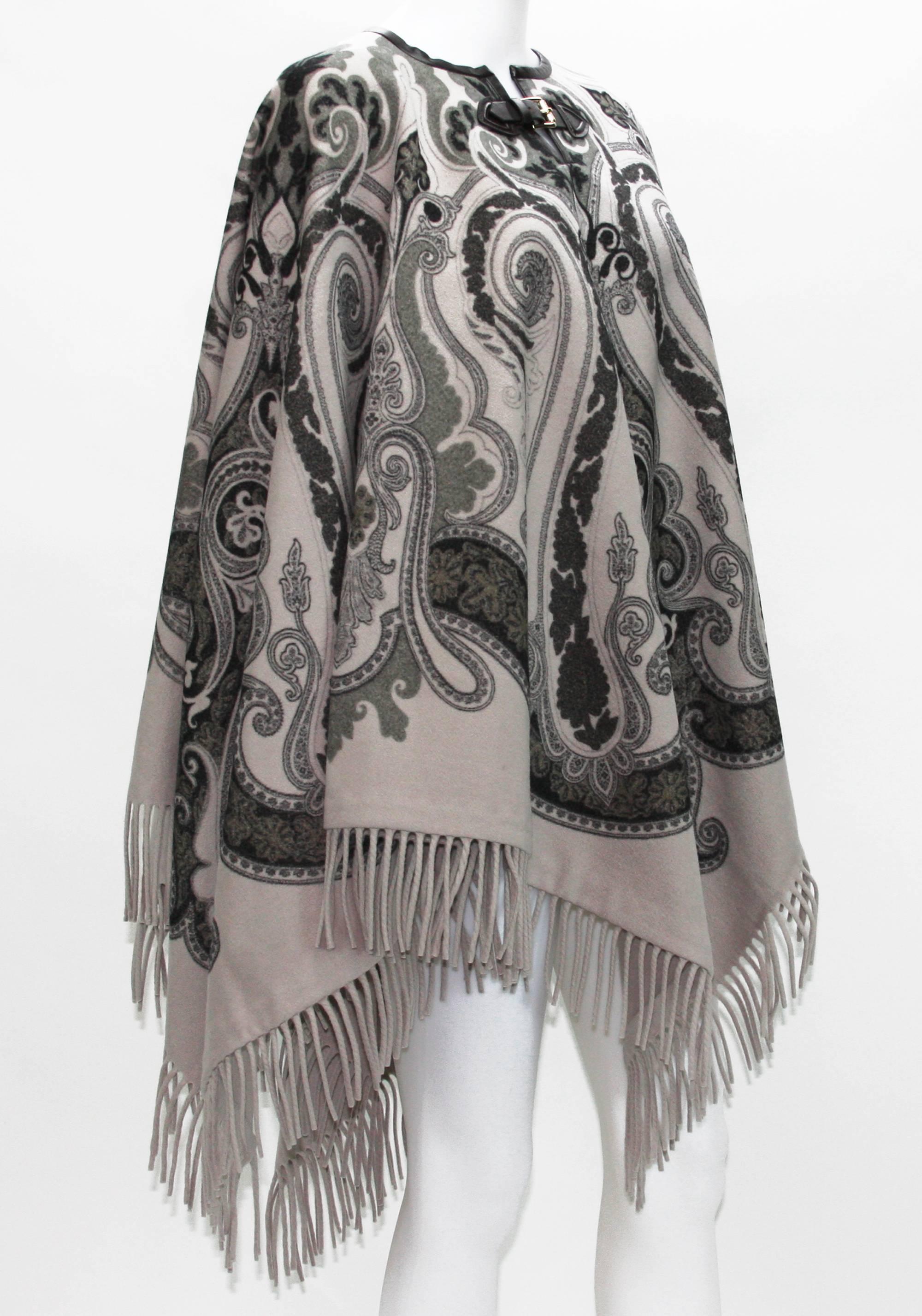 New Etro Wool Poncho Cape

100% Wool

Paisley Design, Fringe Style

Color - Few Shades of Gray

Leather trim with silver tone metal buckle closure

Measurements: 56 inches x 52.5 inches + 3.5 inches fringe from both sides

Made in