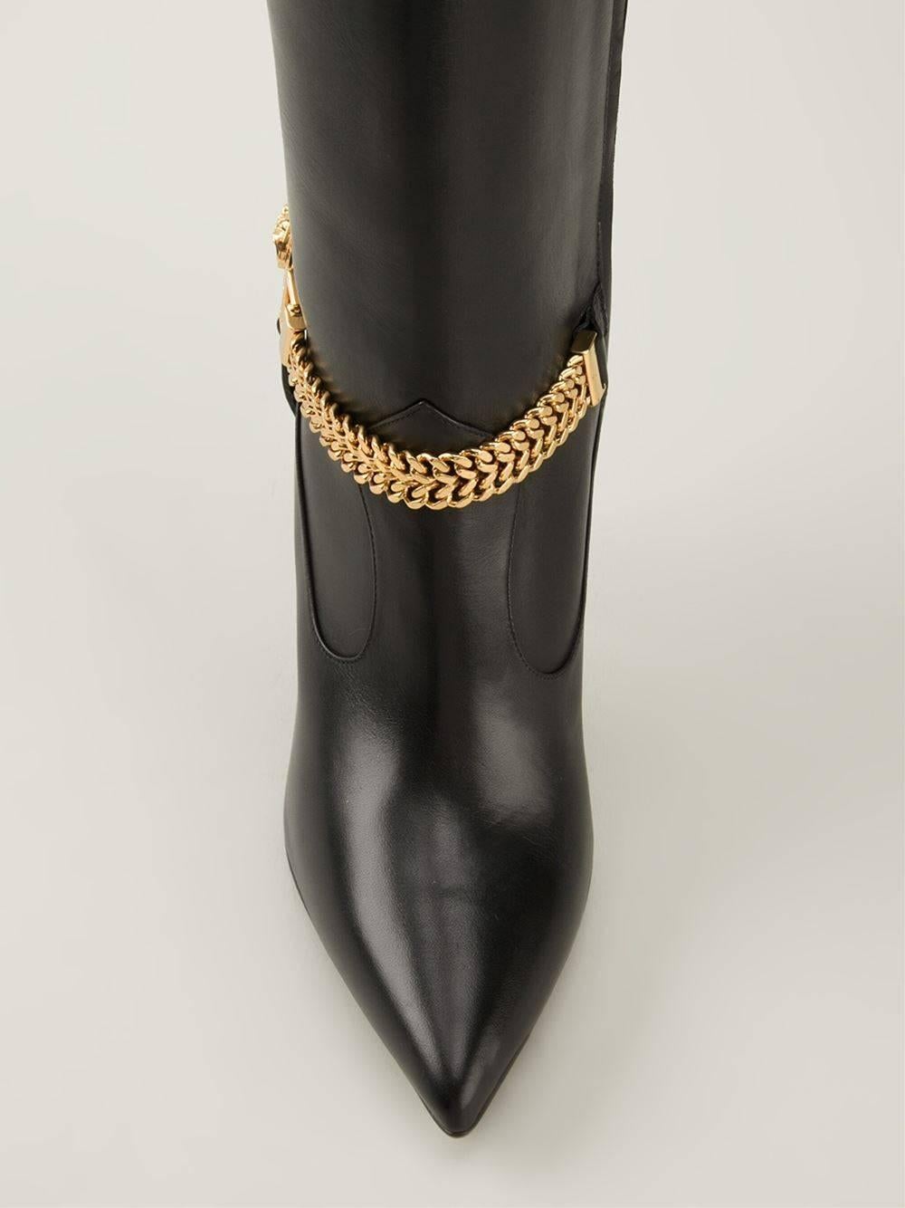 VERSACE BOOTS

Black calf leather Medusa knee high boots from Versace featuring 

a pointed toe, a knee length, a stiletto heel, a side zip fastening and 

a gold-tone chain with Medusa logo.

Made in Italy.

IT Size 36

Brand New, in