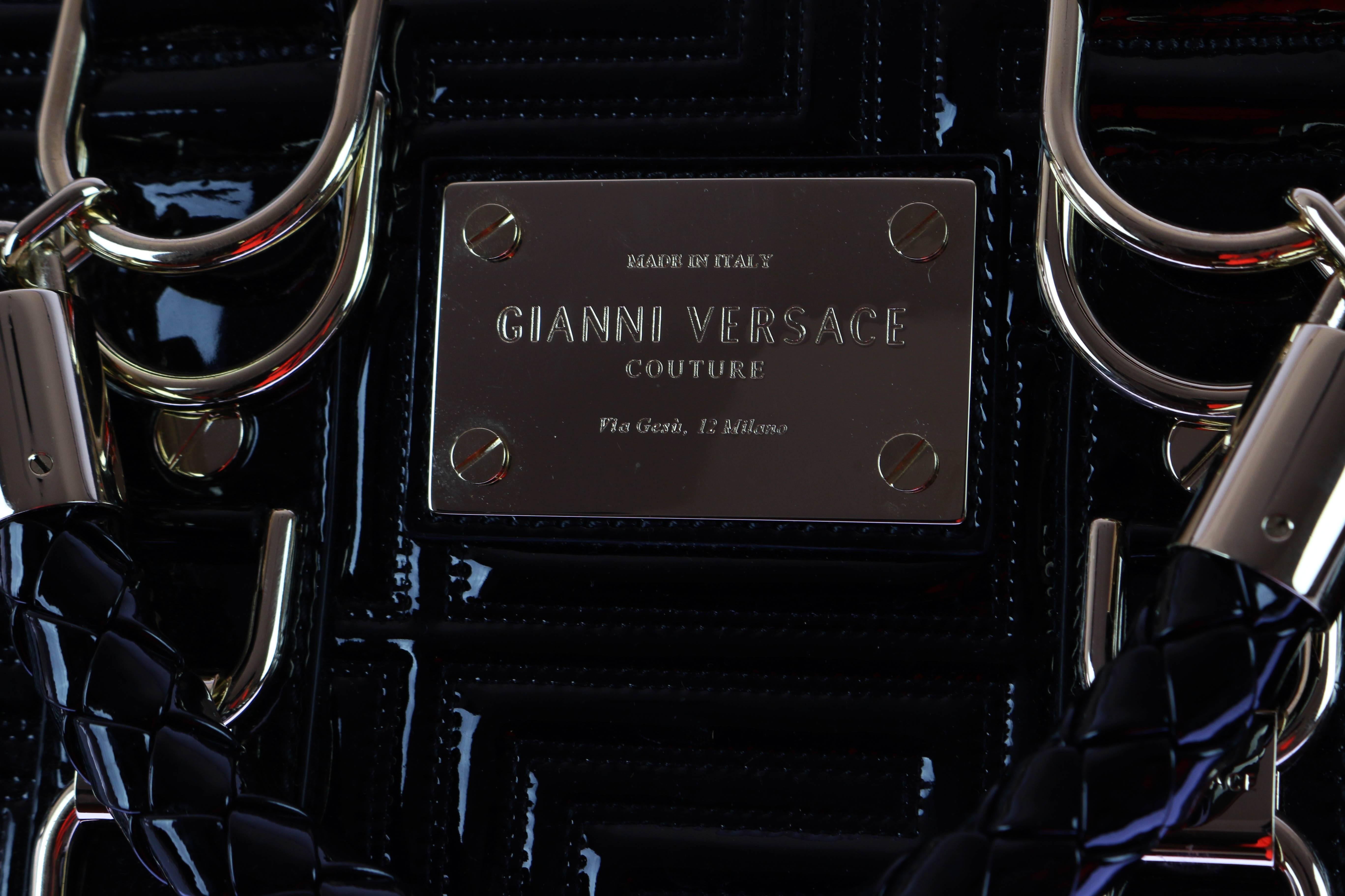 
GIANNI VERSACE COUTURE  Patent Leather Bag

 
 Top zip closure
 
 
 Measures 13'' x 8.5'' tall at center x 7''

Six metal feet at base.

Satin lining with interior zip, patch, and cell phone pockets braided leather top handles with 4''