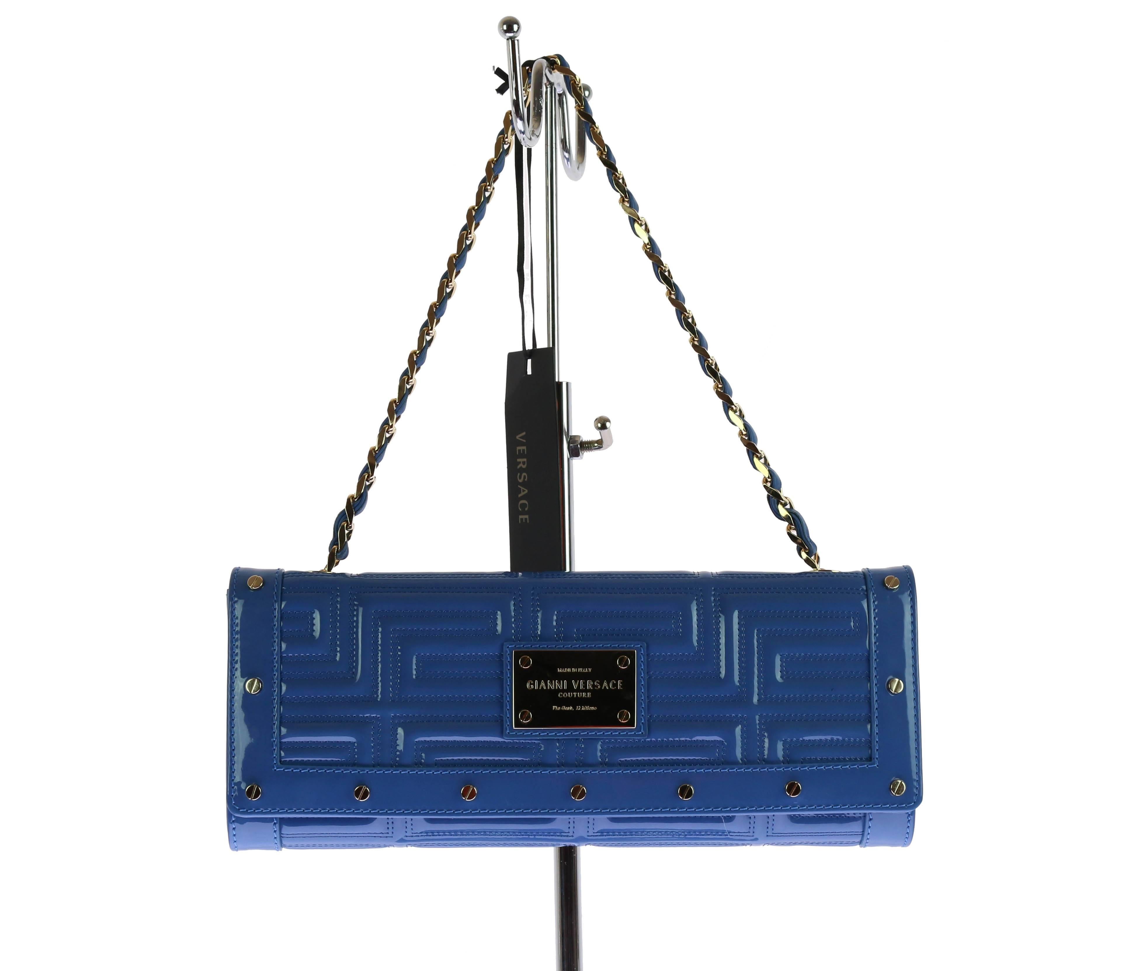 Gianni Versace Couture bag/clutch.
Blue patent leather with Greek Key embroidery.
Removable chain/leather strap.
Gold-tone center plaque.
Snap button.
One internal pocket.
Fully lined.
Measures approximately: 6