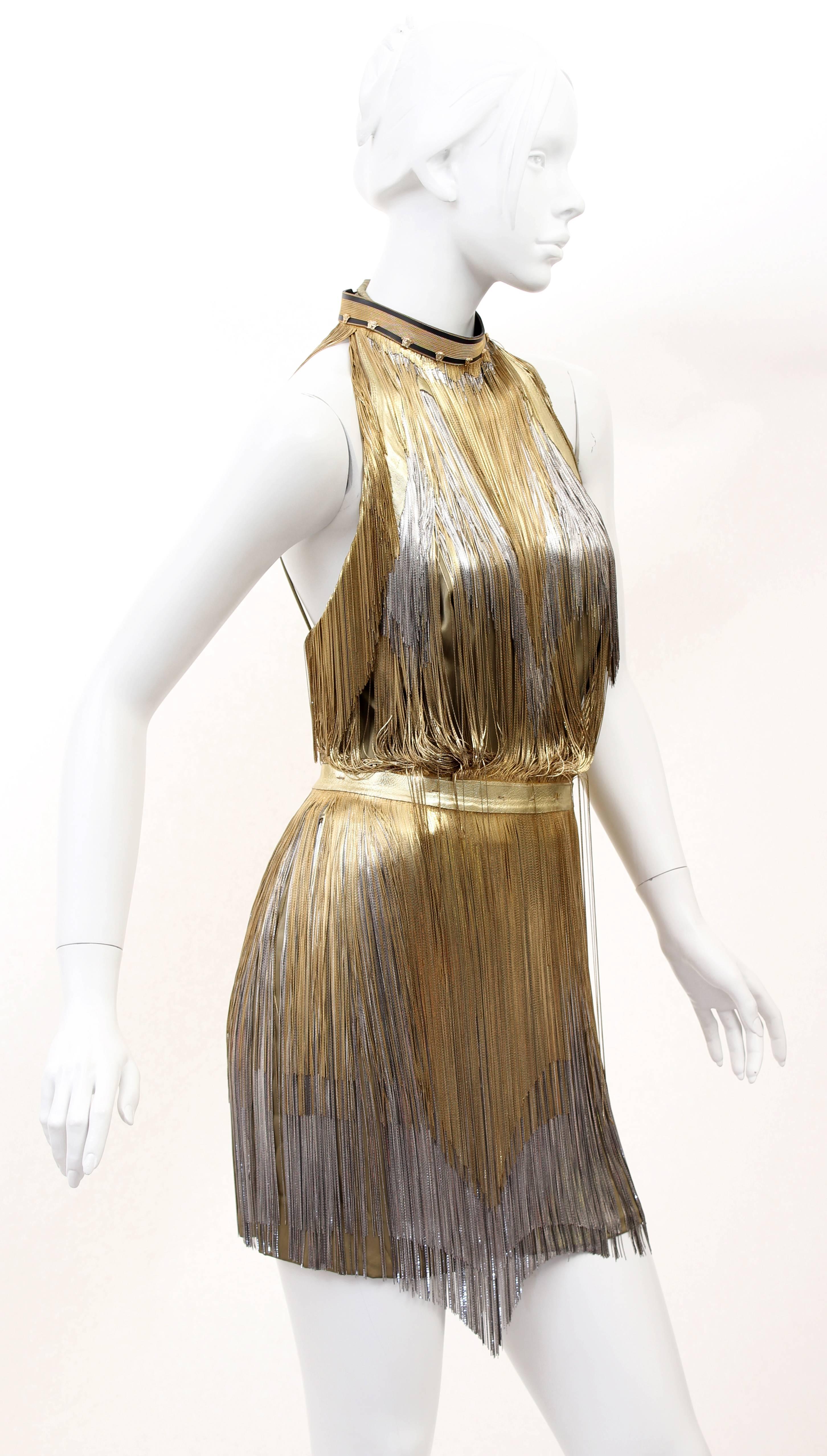 Versace Atelier

Gold Metal Fringe Tie Dyed Gabardine Dress

Tie dyed silk gabardine base with all over metal fringing. 

Halter neckline with leather strap and buckle closure at back. 

Detachable leather belt with buckle closure. 

Metal fringing