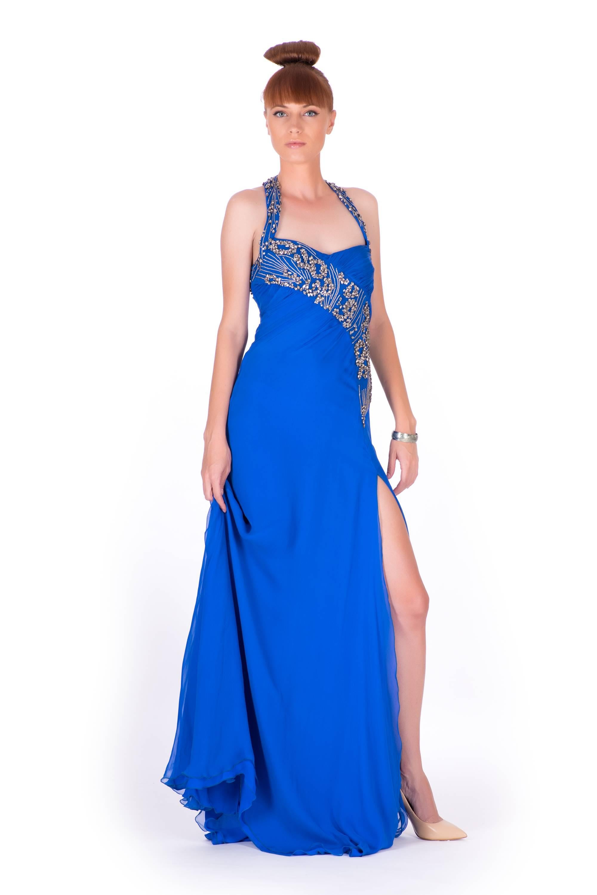 New VERSACE EMBELLISHED ROYAL BLUE
CHIFFON SILK GOWN

Impress at any formal function with this elegant
creation by Versace. The royal blue dress was
fashioned in Italy with luxurious silk chiffon. An
artfully embellished body with an open back,