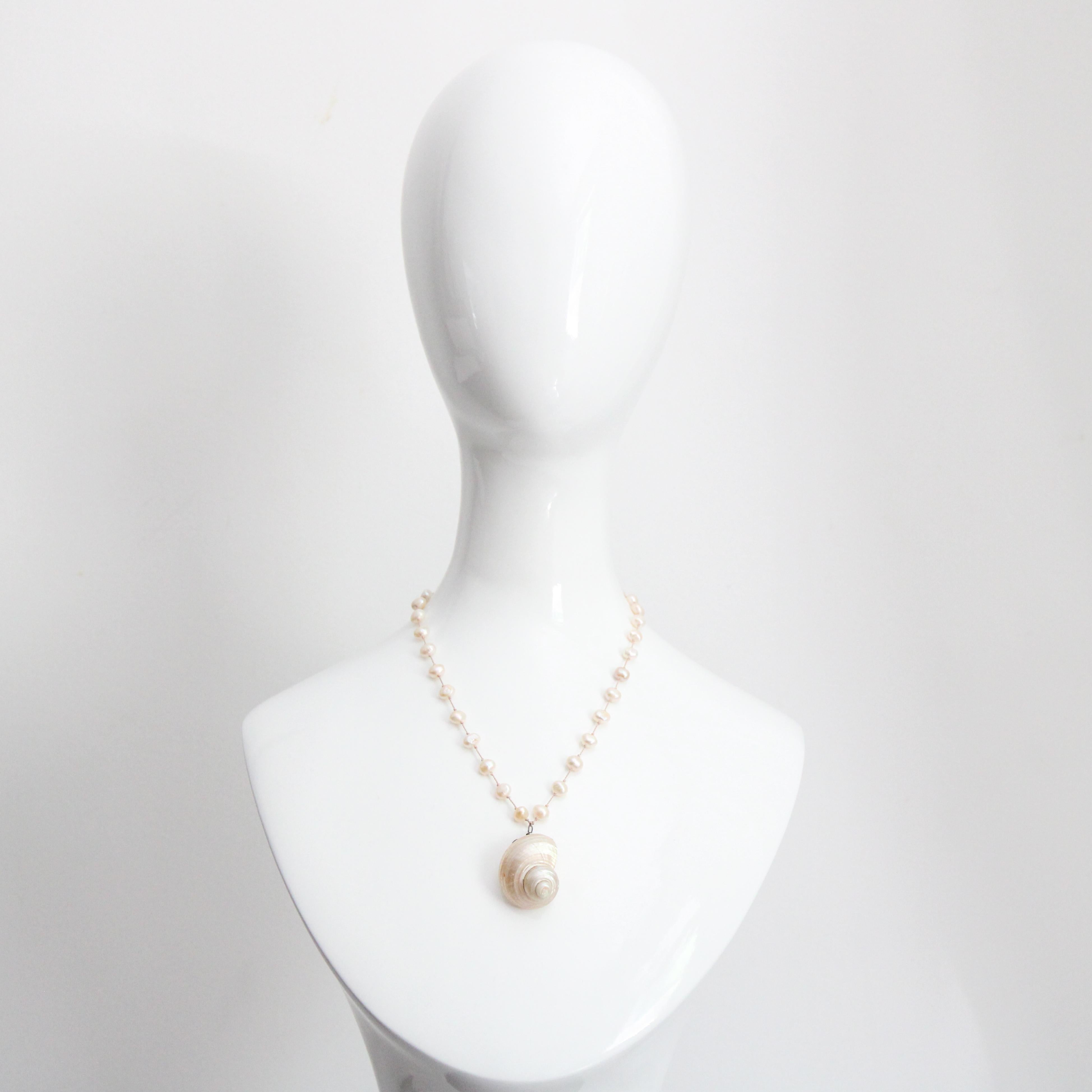 Un'ode all'oceano, questa collana vintage di perle e conchiglie con finiture in argento sterling è il tocco finale più delicato per il tuo abbigliamento.

La base in filo di seta annodato a mano è impreziosita da perle vere e proprie, che
