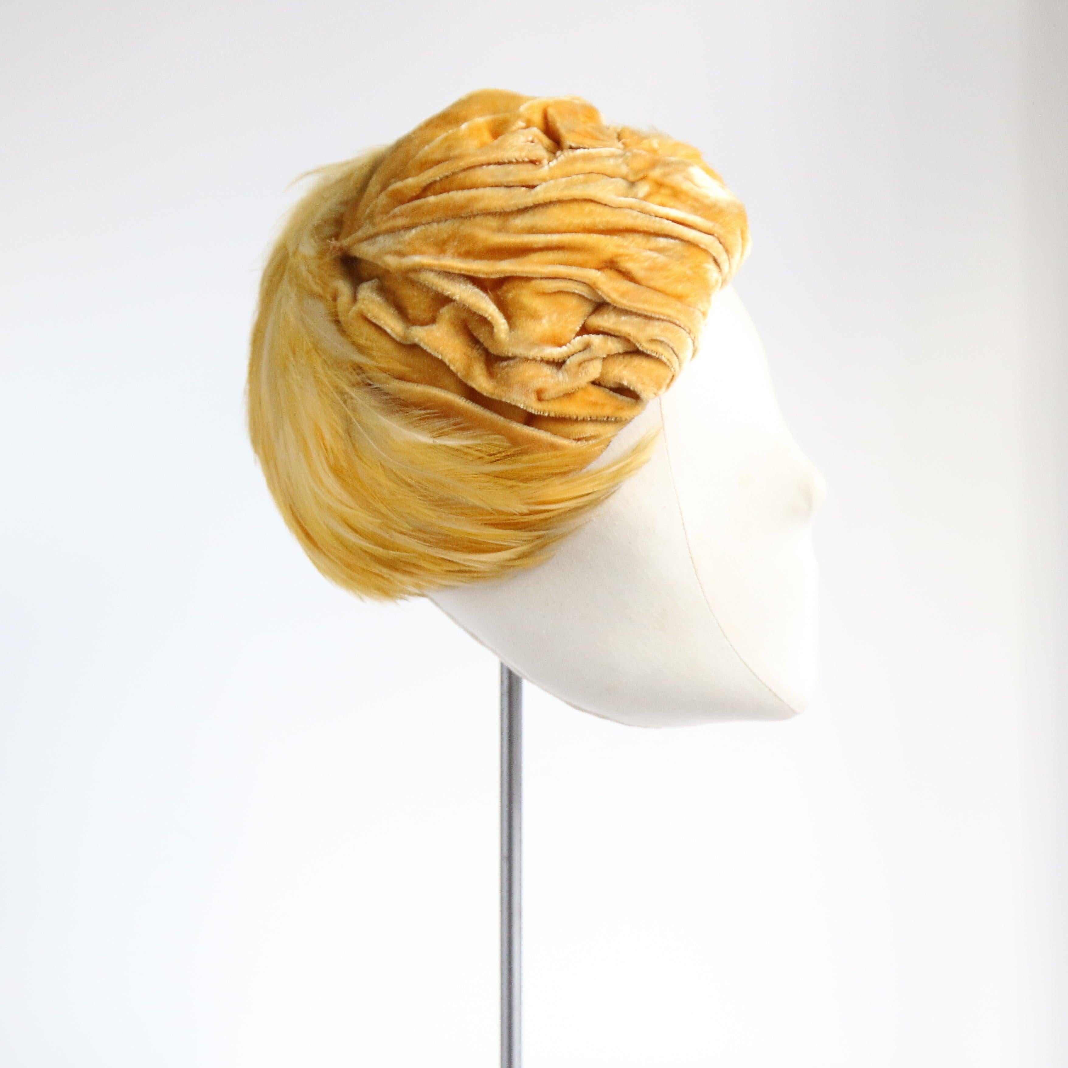 Questo divino cappello anni '40, in una splendida tonalità di giallo sole, è il tocco di colore perfetto per completare il tuo outfit.

La splendida corona in velluto plissettato è arricchita da piume giallo narciso sul davanti che terminano con un