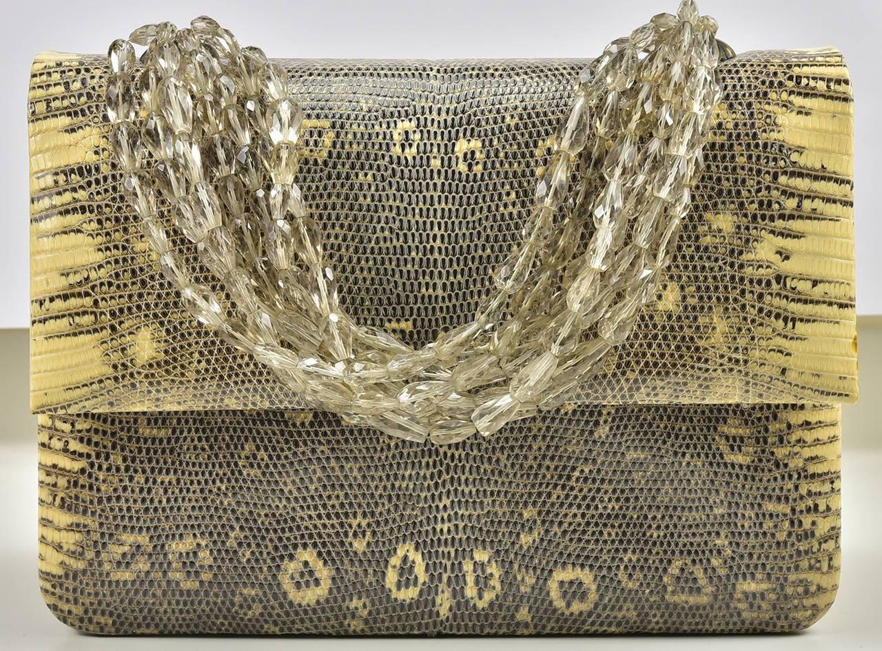Iconic and always classic, this beautiful Darby Scott lizard bag is season-less and timeless.  The perfect size for all occasions, day and night. and neutral in color. Pristine condition. Handle is removable so may be worn as a clutch.