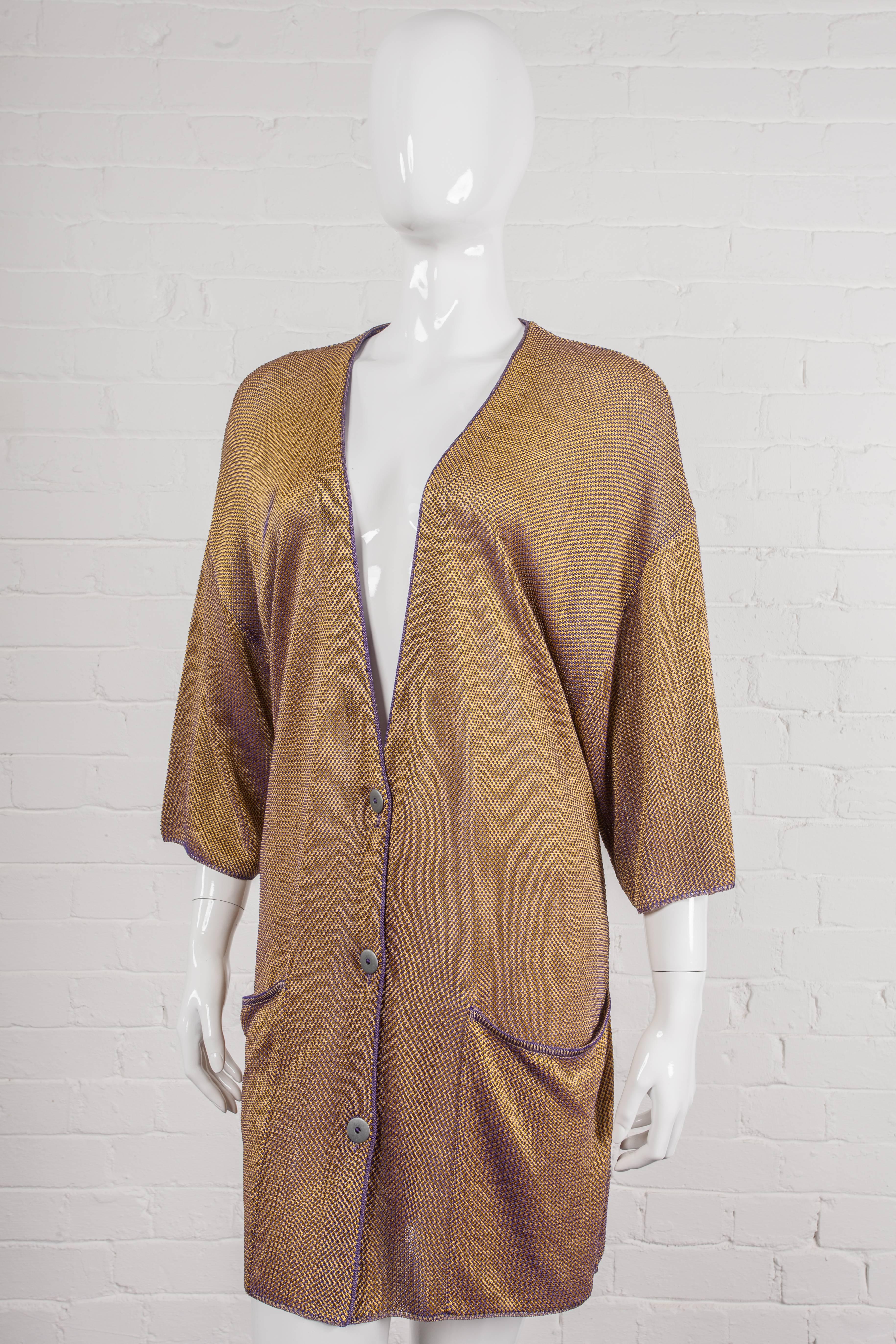 A loose-fitting ‘V’ neck style cardigan with drop shoulders and three-quarter length sleeves. Features an changeant opalescent gold and purple contrasting stitch effect, metal buttons and large patch pockets to the front hem.

Period: 1980s –