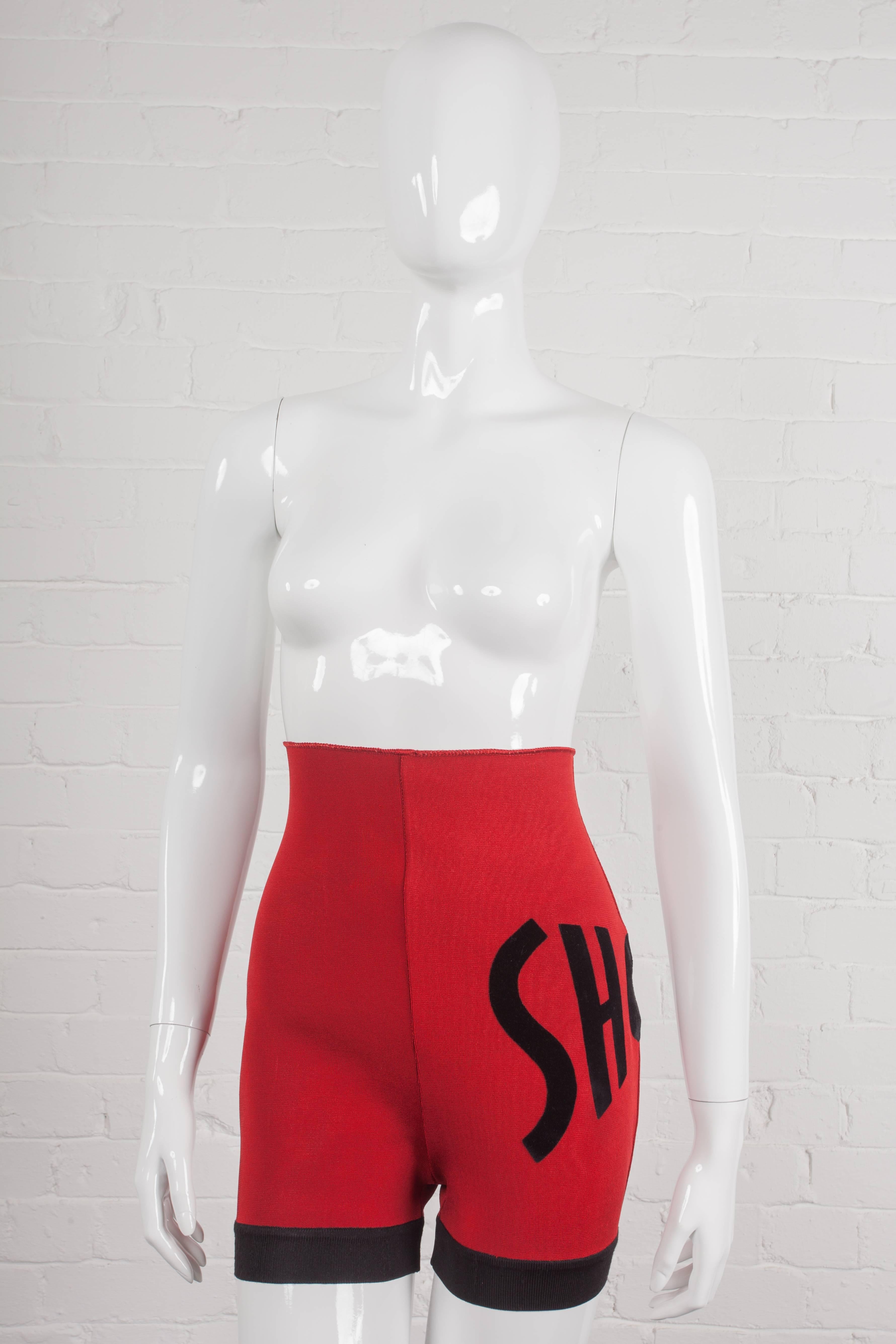Fitted stretch shorts in red with a black trim, waistband-free high-waist from the Jean-Paul Gaultier Spring/Summer 1990 “Rap’Prayers” Collection. Featuring the word ‘short’ in capital letters as a velvet motif and with a cut out hole in the ‘o’