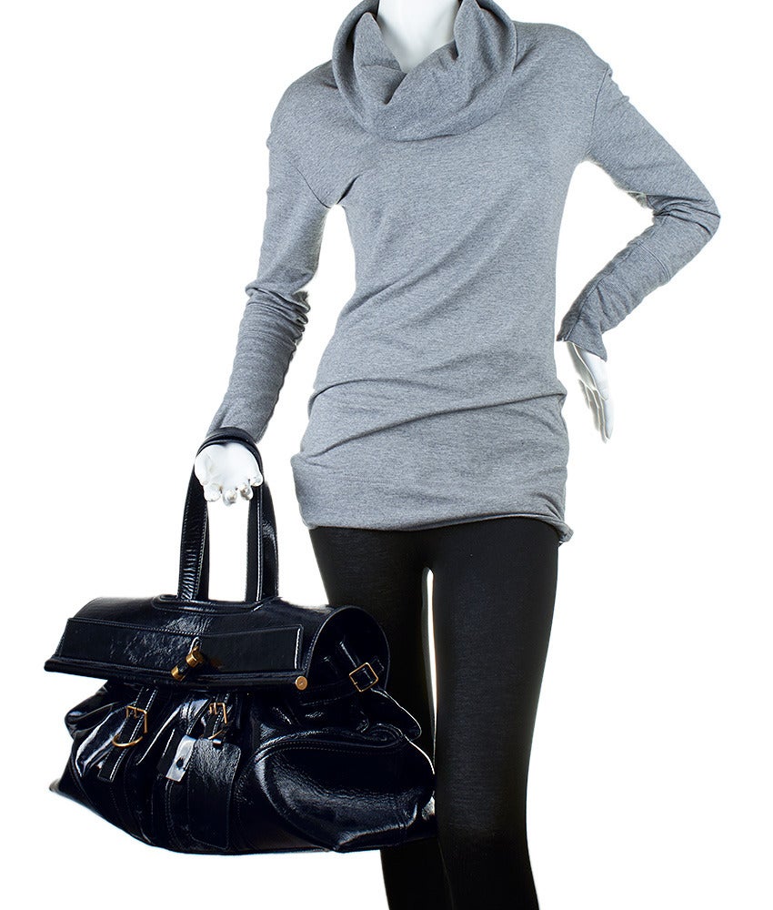 This YSL Weekender duffle features a flap closure with a functioning gold-tone lock, as well as adjustable leather straps on either side. The top flap features an internal metal bar at one side for added durability. This is the perfect bag for