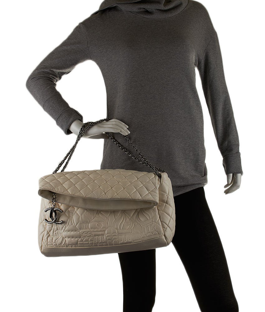 This Chanel Moscow collection shoulder bag features a zippered closure with a fold over flap. The shoulder strap and hardware are made of pewter-tone metal that complements the white leather. The zipper pull features a roped logo detail in the same