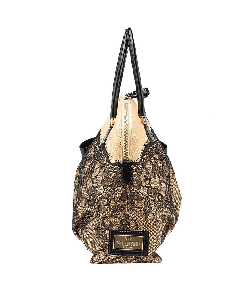 This Valentino Bow satchel comes in beige raffia with a beautiful lace detail overlaying the majority of the exterior. It features a top zippered closure and a luxurious satin lining. The bag also features a charming patent leather bow on the bottom