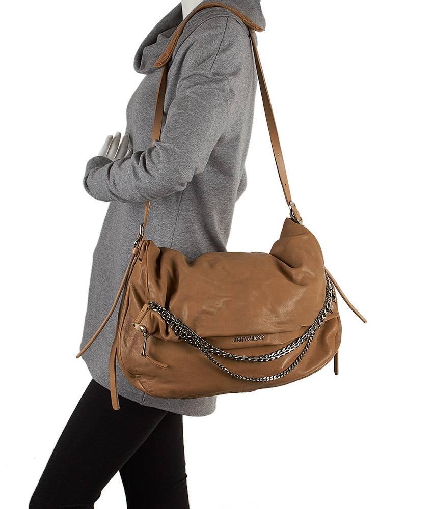 This Jimmy Choo Biker bag comes in a beautiful tan leather with silver-tone hardware. The adjustable shoulder strap has an additional quilted leather pad for comfort. The zipper pull features an edgy chain detail that has diamond, heart, and spade