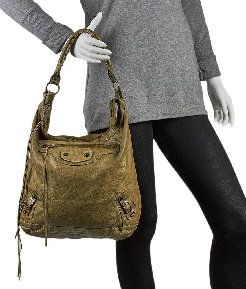 This Balenciaga Day hobo comes in a beautiful olive green color with gold-tone buckles and studs. The entire bag has a weathered look, even though the bag is barely used. The handle features a braided detail, and the bag has a top zipper closure, an