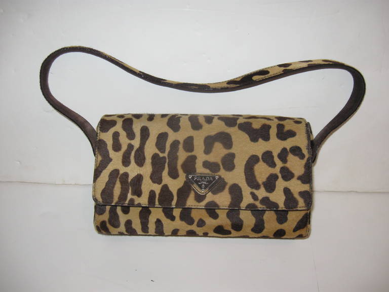 Wonderful stenciled leopard hide baguette style shoulder bag by Prada, in beige with dark brown markings.  Hidden snap closure with brown suede interior and interior zippered pocket.
Handles stands 8.50 inches above the body.