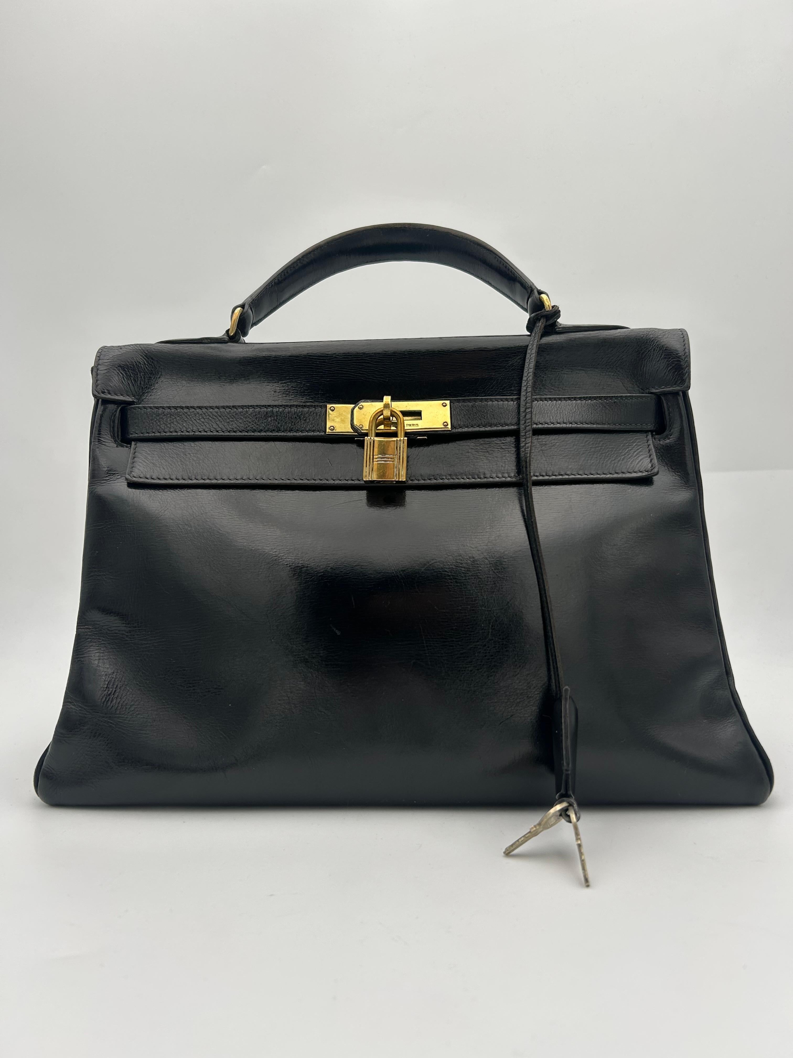 La borsa Hermès Kelly del 1998 in pelle Box nera è un pezzo iconico e senza tempo, che esemplifica la dedizione del marchio all'artigianato impeccabile e al lusso sobrio. Realizzata in pelle di vitello Box - un materiale liscio e lucido noto per la