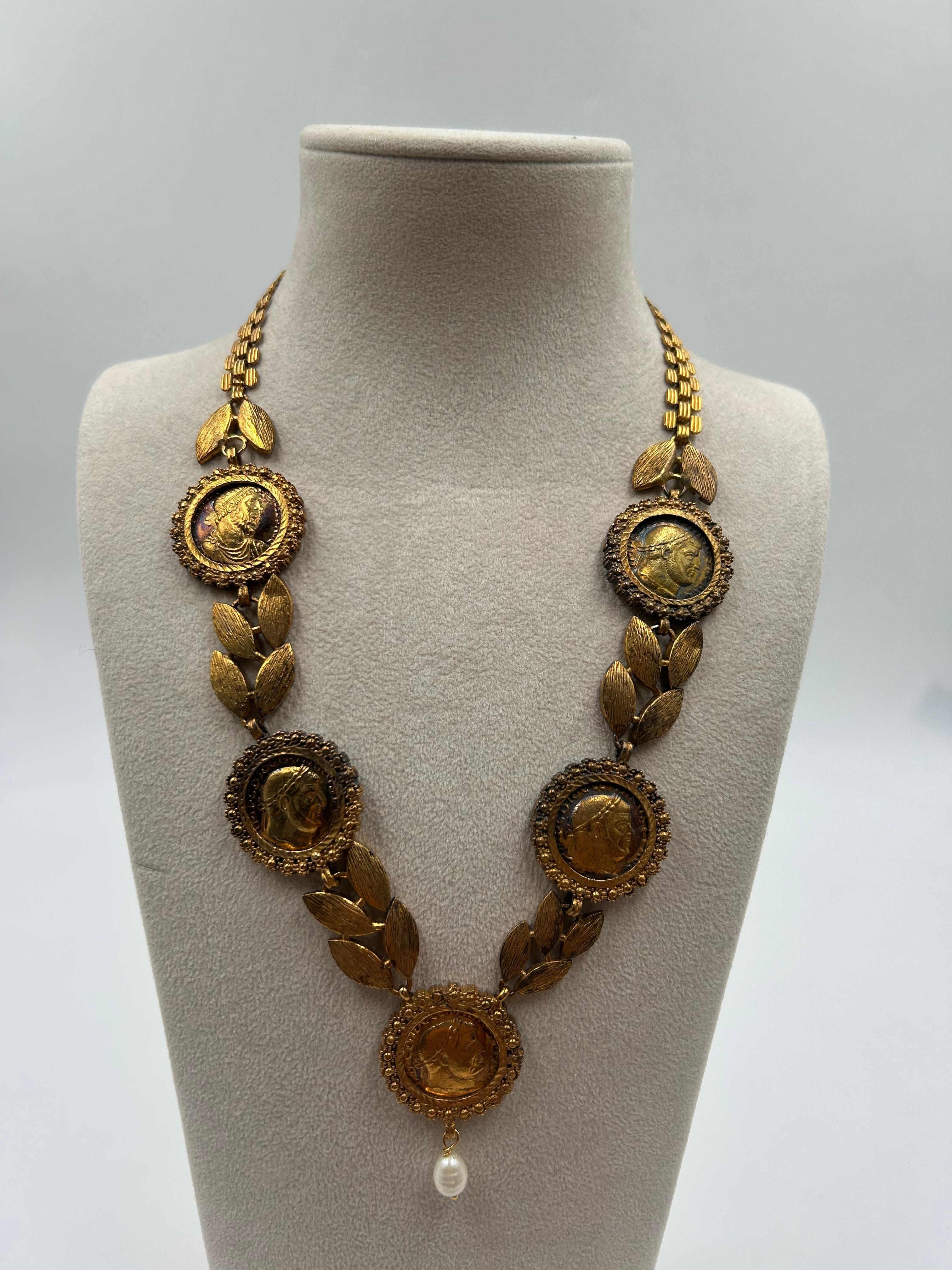 Collana con monete, foglie di alloro e perle in ottone.   Regale e raffinata, questa collana in ottone dorato presenta un'intricata combinazione di medaglioni di monete, motivi di foglie di alloro e perle lucenti. Ispirato all'eleganza classica, il