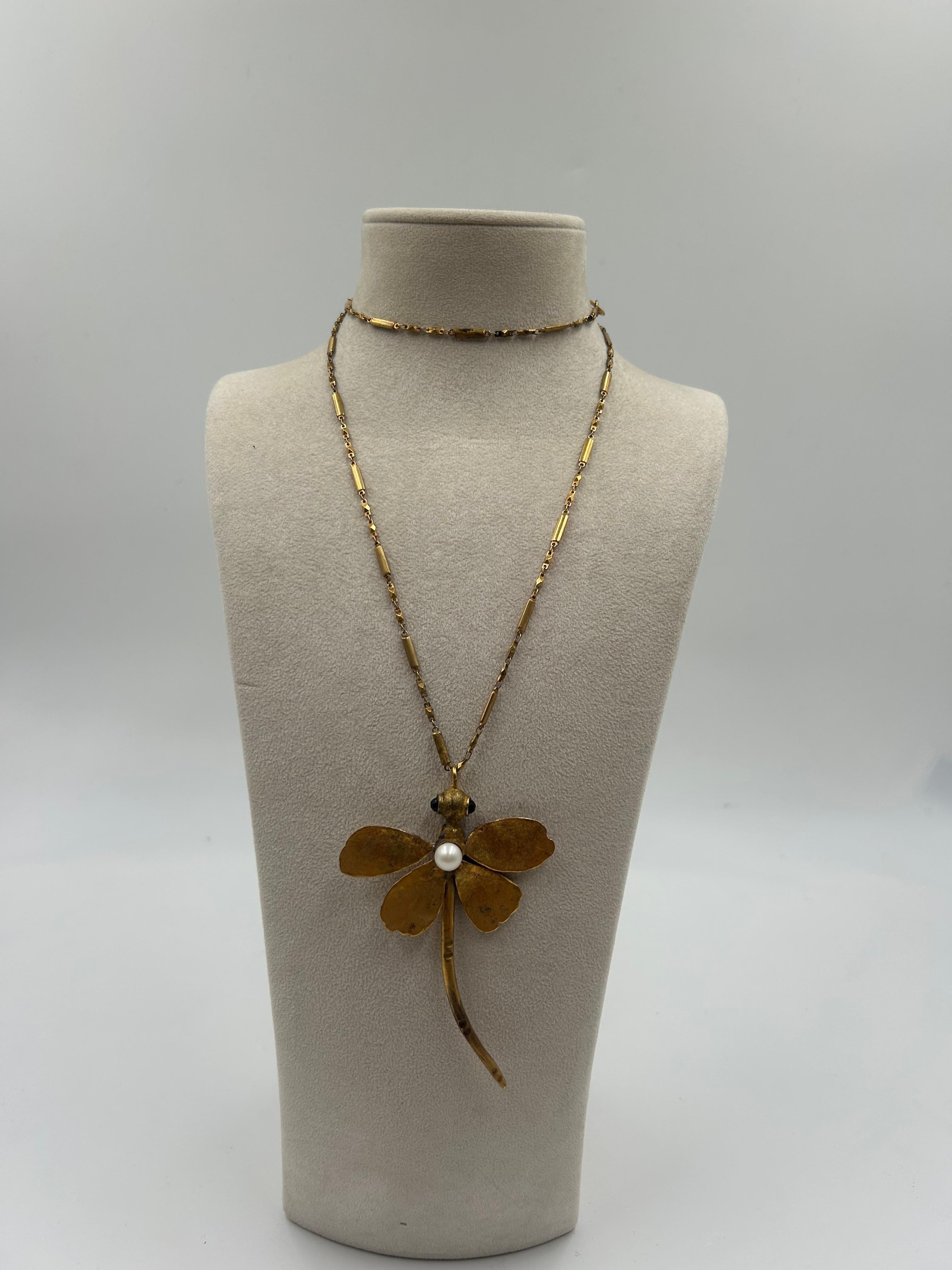 Elegante e incantevole, questa collana in ottone dorato presenta un motivo a libellula splendidamente dettagliato e arricchito da perle finte brillanti. Il design fonde l'ispirazione naturale con il fascino vintage, offrendo un look sorprendente ma
