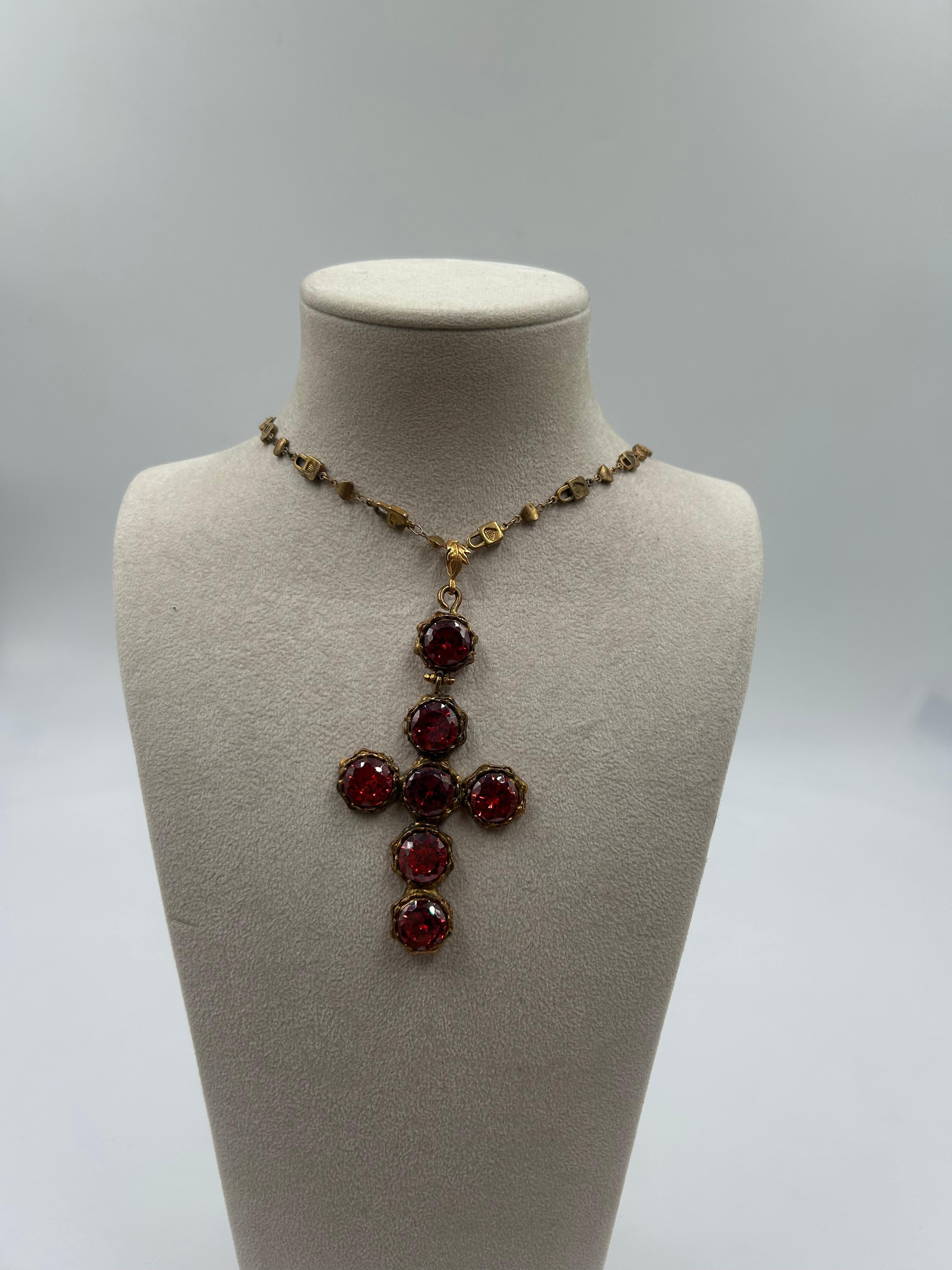 Drammatico e accattivante, questo ciondolo a forma di croce penzolante in ottone rosso e dorato è un vero pezzo forte che unisce l'eleganza vintage a un design audace. La croce, ricca di dettagli, presenta vibranti accenti di smalto rosso che creano