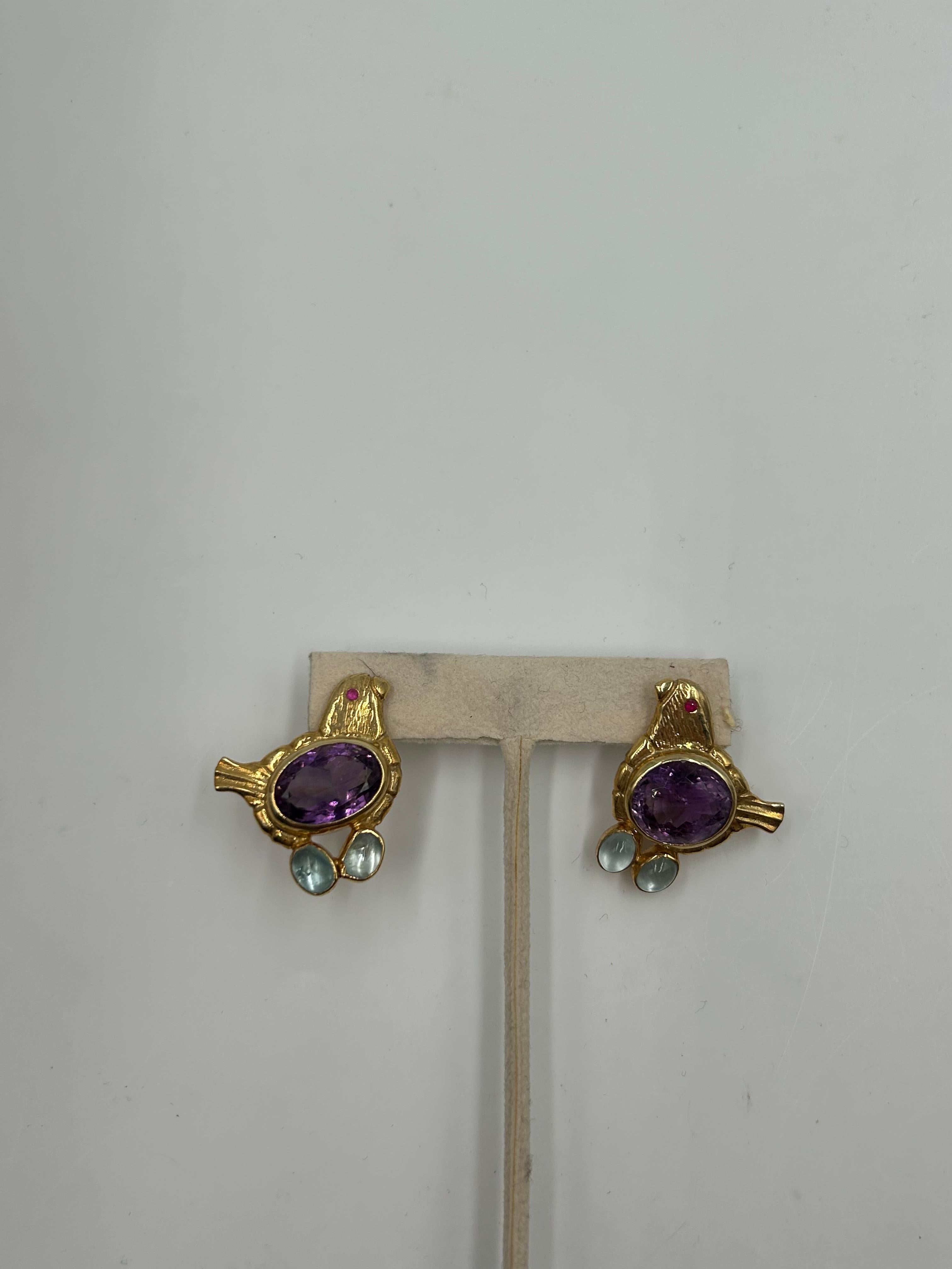 Questi orecchini vintage in argento dorato, unici e realizzati ad arte, presentano un design intricato con vere pietre viola per un tocco di naturale eleganza. Il motivo dell'uccello scolpito aggiunge un fascino stravagante, mentre la ricca finitura