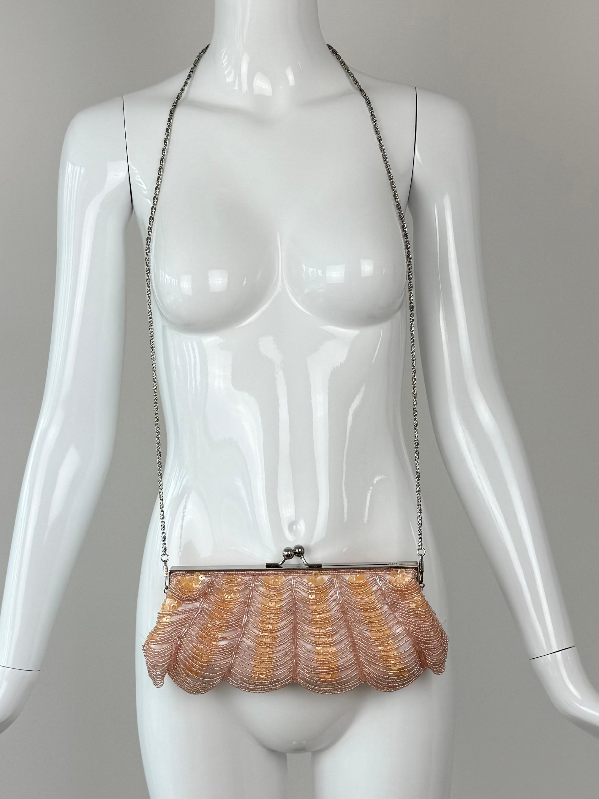 Randolph Duke The Look
Vintage
2000's
Perles festonnées rose pâle drapées de paillettes orange
Le sac est muni d'une longue chaîne en argent qui peut être enlevée ou rentrée dans le sac, ce qui permet de l'utiliser comme une pochette.
Une chaîne