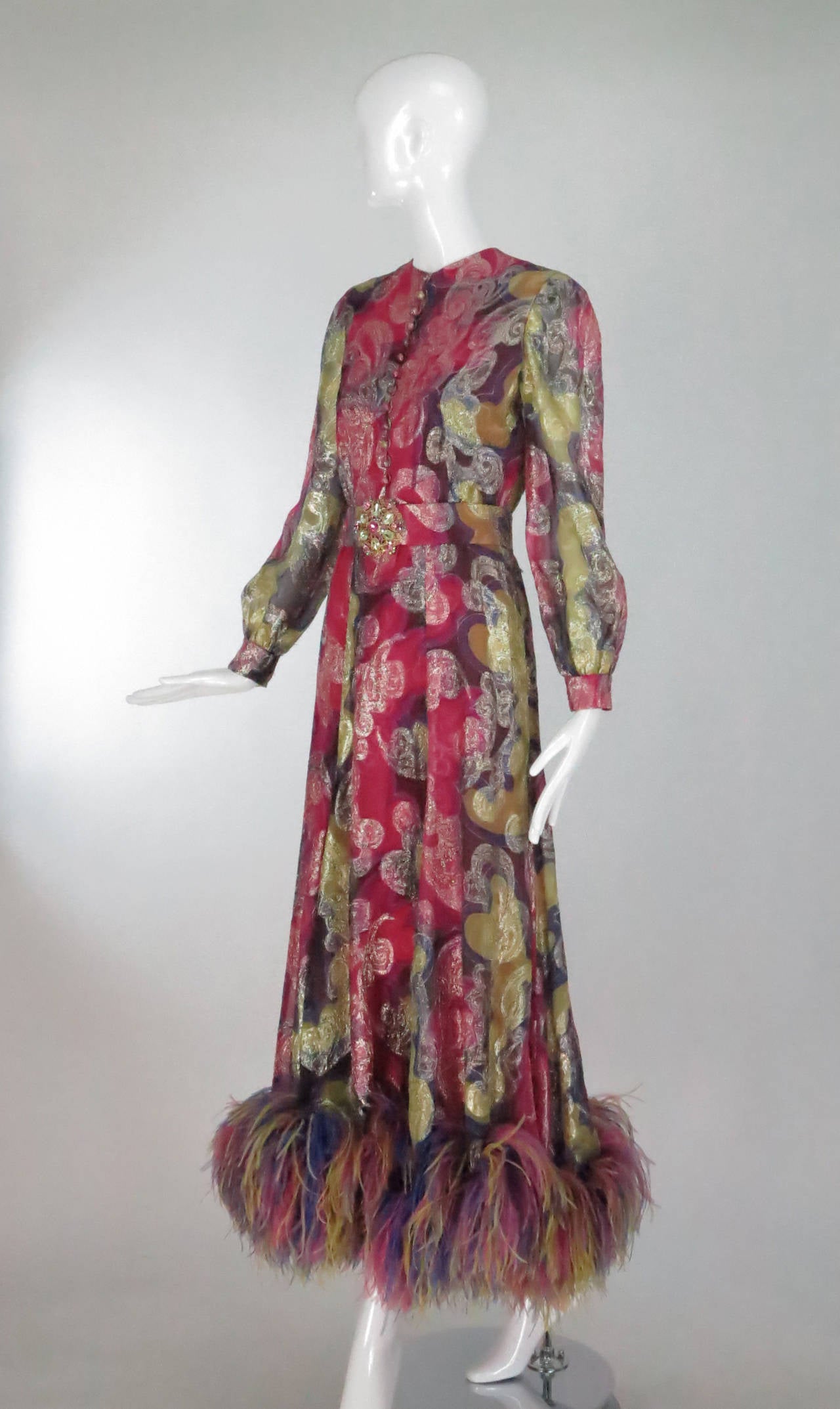 Fabulous metallic chiffon brocade gown from the early 1970s designed by Oscar de la Renta...Light as air fabric in shades of pink, purple, yellow & blue that sparkles with gold metallic threads, the hem has a deep band of ostrich feathers in the
