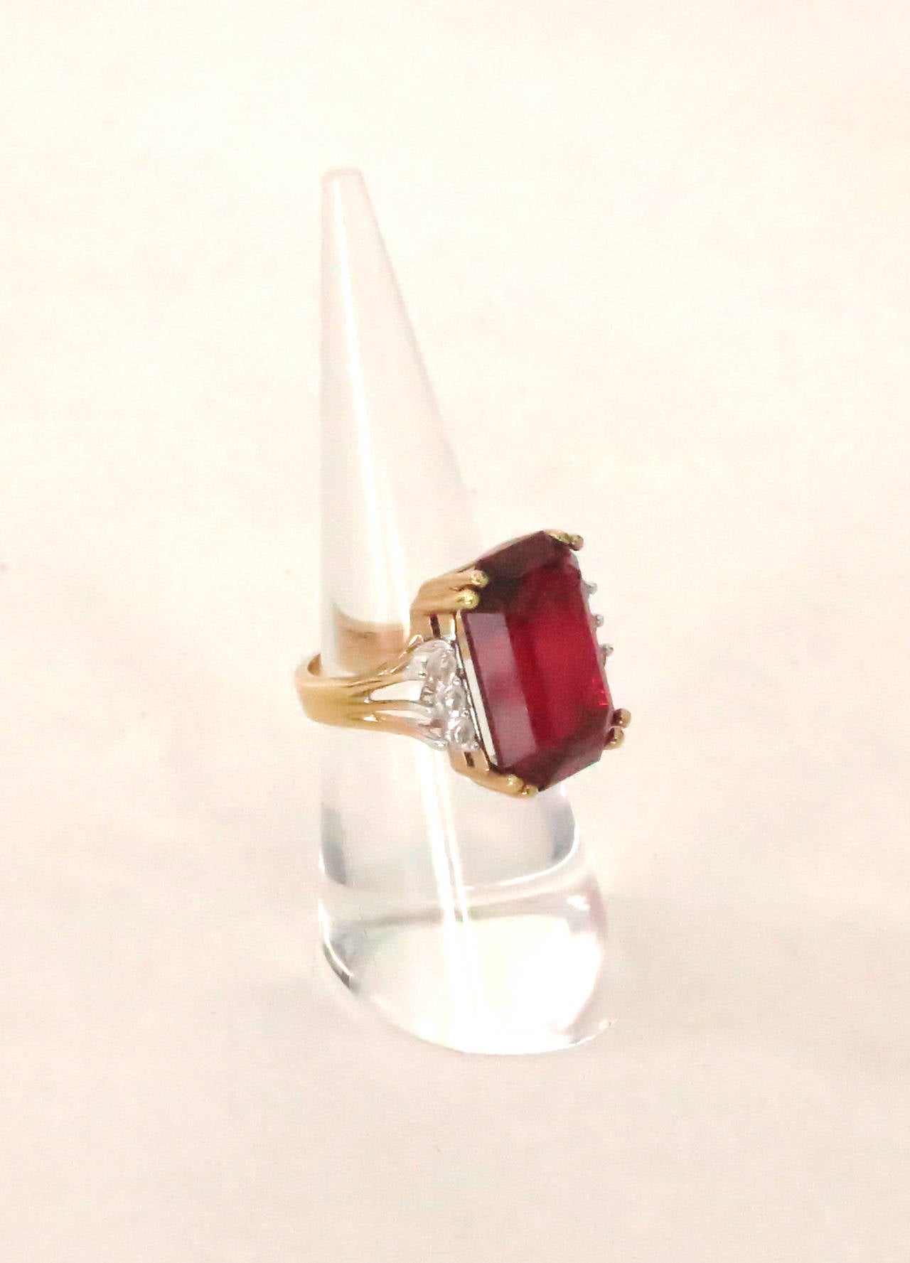 Faux emerald cut ruby & diamond ring set in gold...A large & beautiful faux ruby is prong set with three sparkling faux diamonds at either side...Barely worn and in excellent condition without scratches or chips...Fits a size 5.