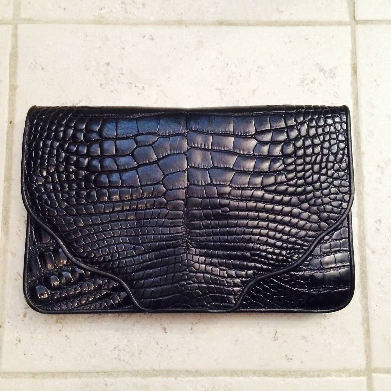 Large size black alligator envelope clutch handbag from the 1980s by Varon...Deep front flap closure with hidden snap...The front and back of this bag are alligator, the hidden side vents are pressed black leather...The bag is trimmed in black