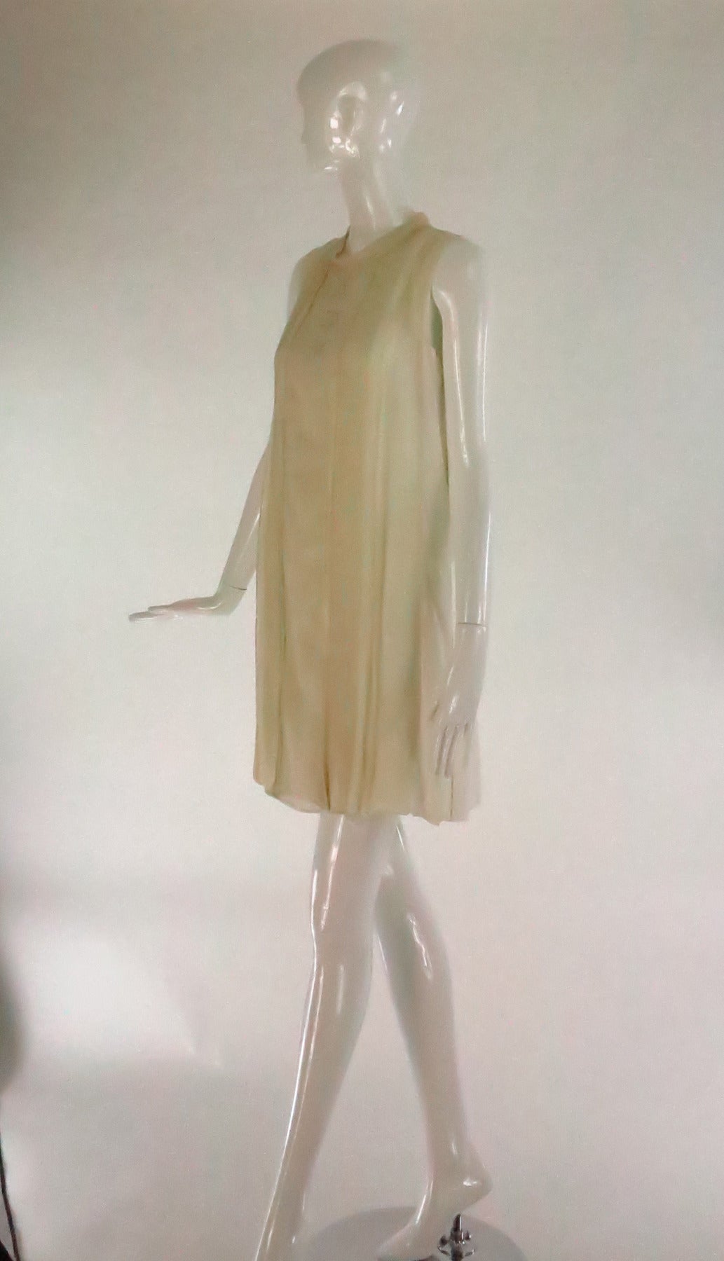 Cream chiffon and crepe sleeveless dress by Chloe...High round stand away collar, the front of the dress has tiny pin pleats at either side front to hem, the center front has a row of decorative buttons...The back of the dress has a dropped waist
