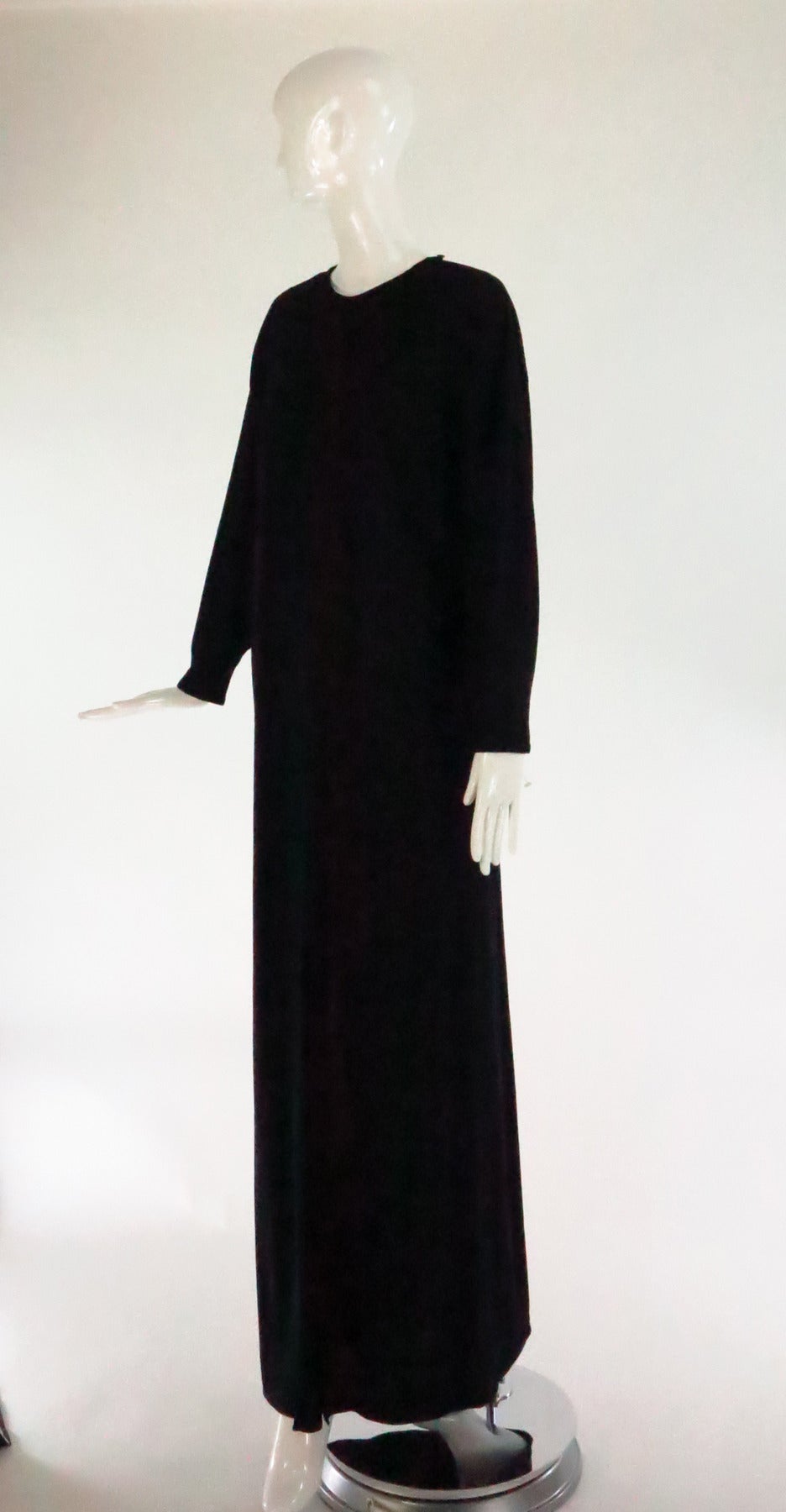 Statement making design from Geoffrey Beene, new with the original tags from the 1970s...Casual maxi dress in fine soft black wool knit...The dress is unlined...Pull on style that closes at each shoulder side with a loop and button...Long dolmen