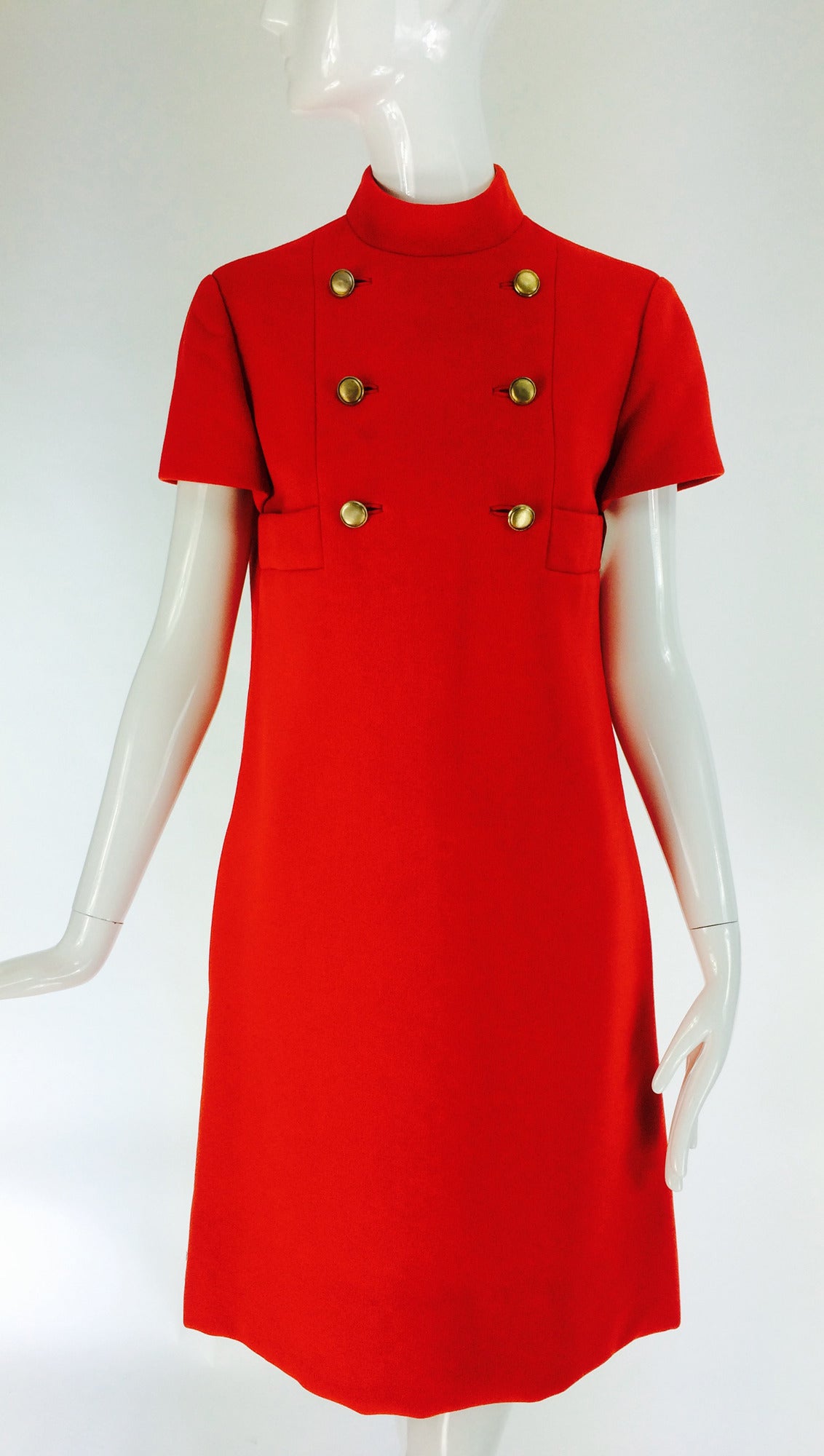 Geoffrey Beene coral red wool crepe mod style shift dress from the 1960s...High banded collar with short sleeves, the fitted A line shape dress has a double row of brass buttons at the bodice front and banded pockets at each side front...Fully lined