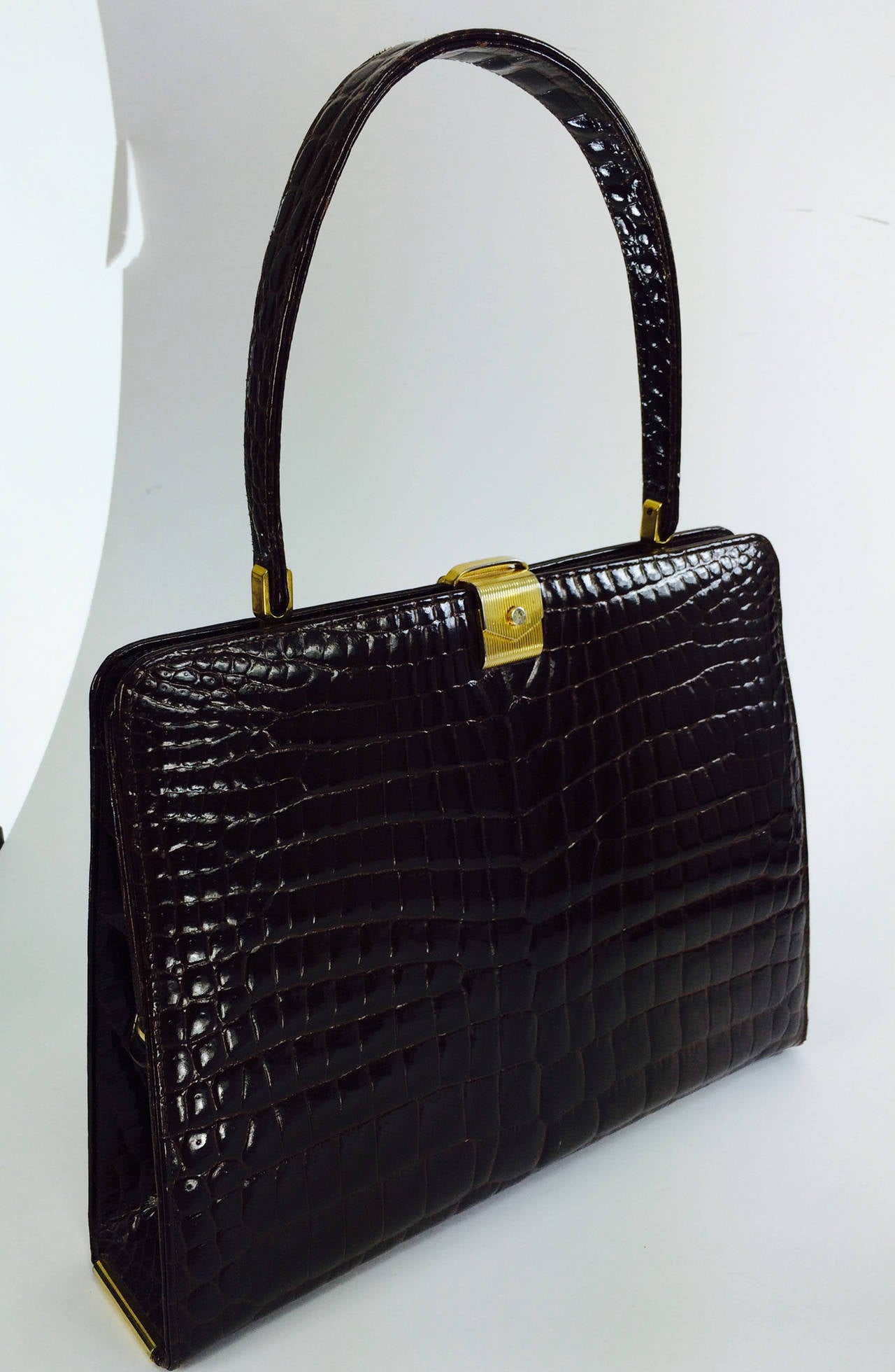 Gorgeous deep chocolate brown glazed alligator handbag by Dofan from the 1960s...Frame bag with gold hardware, unique clasp at the front looks a bit like an envelope, instead of 4 feet on the bottom there are rolled gold tubes at each bottom side