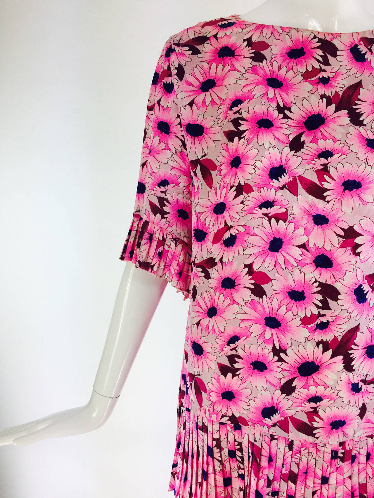 Daisy print tunic top in pink figured silk with blue eyed daises...Round neckline top has loose fitting elbow length sleeves that have pleated cuffs...The tunic is cut straight and has a pleated hem...Unlined...Closes at the back with a