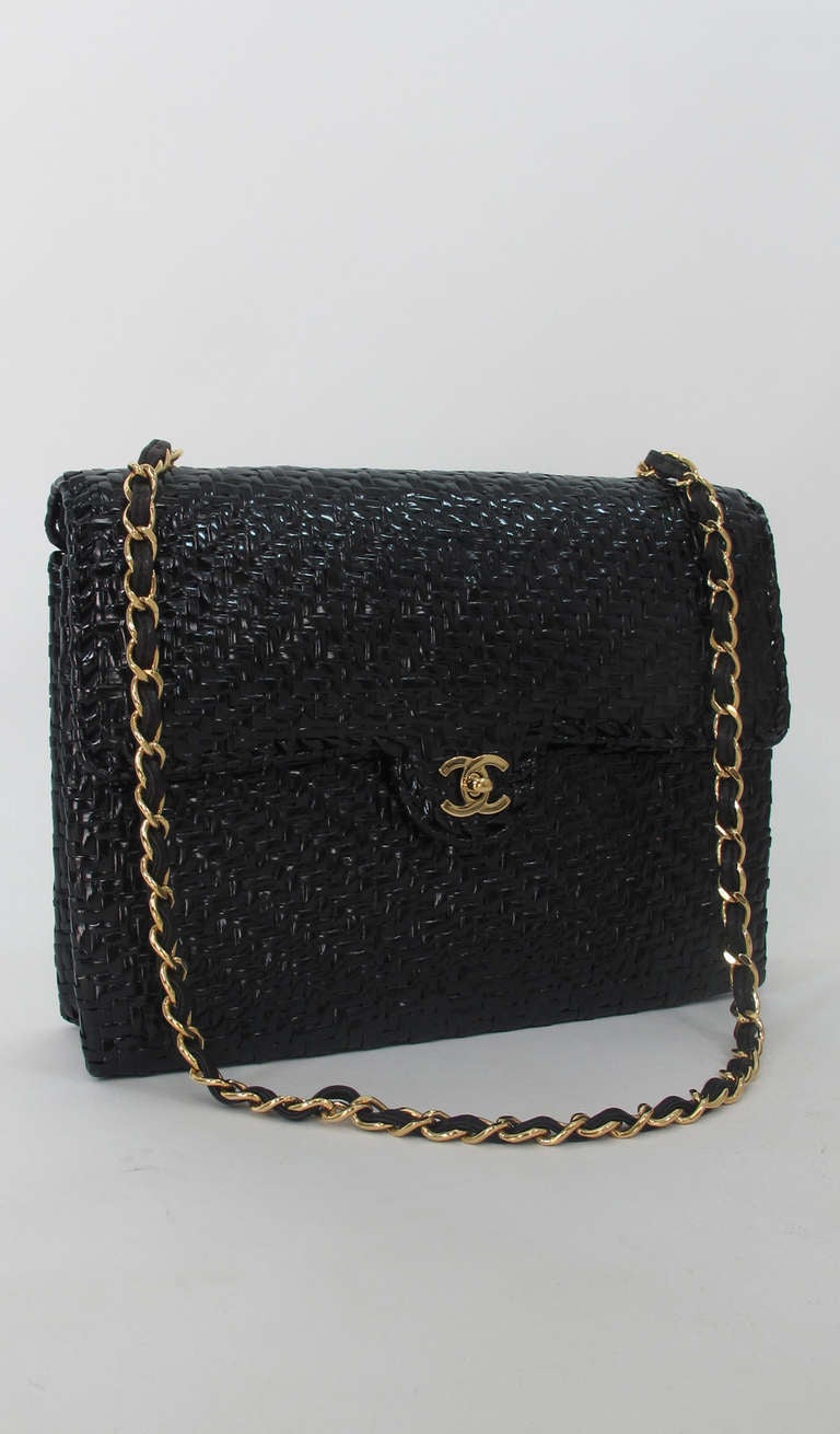 Large size Chanel black lacquered wicker shoulder bag...Flap style with chain strap woven with black leather...Bag is lined in black faille, there is one inside compartment at the back with a zipper closure & logo pull...In excellent