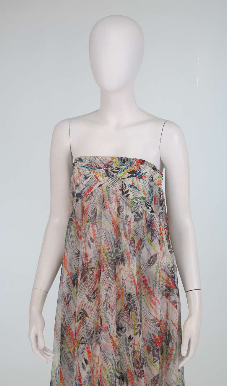 John Galliano silk chiffon strapless tiered gown...Mid century inspired print...Fitted band at bust top (under arm), with X banded design at front bust and back, with a flowing over layer that reaches below the knee...The under dress is a bias cut A
