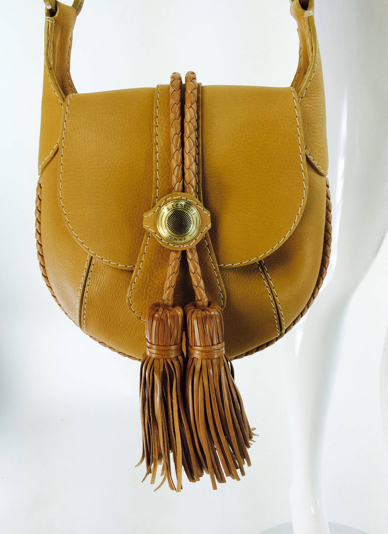 A. Testoni, femme, fringe tassel shoulder bag in warm caramel lightly textured leather...This bag is a great size and not overwhelming, fits perfectly under your arm...The bag closes with a flap that has large decorative fringe tassels with a logo