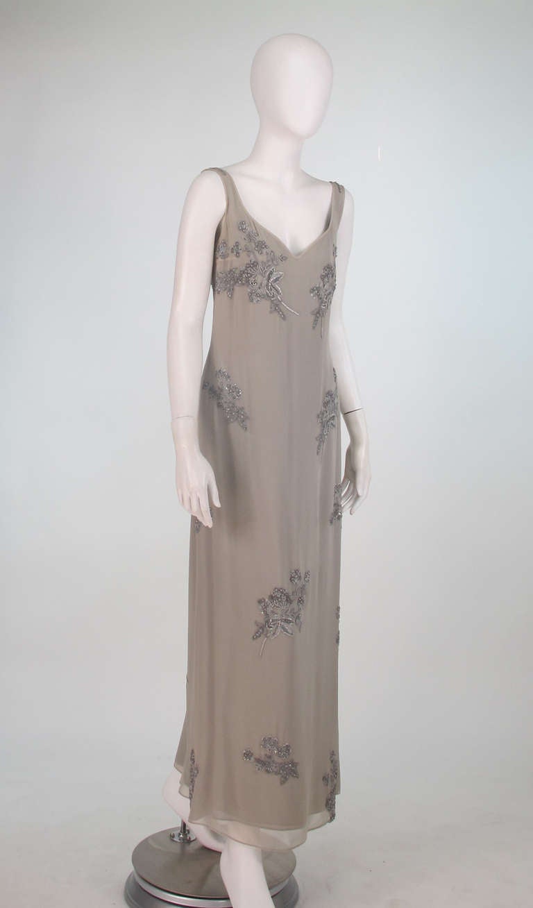 1990s Georgio Armani beaded silk gown in dove grey...Layered sleeveless silk chiffon evening dress has a low scoop neckline, front and back...Beaded floral designs in silver with rhinestones throughout...Closes at the side with a zipper...There are