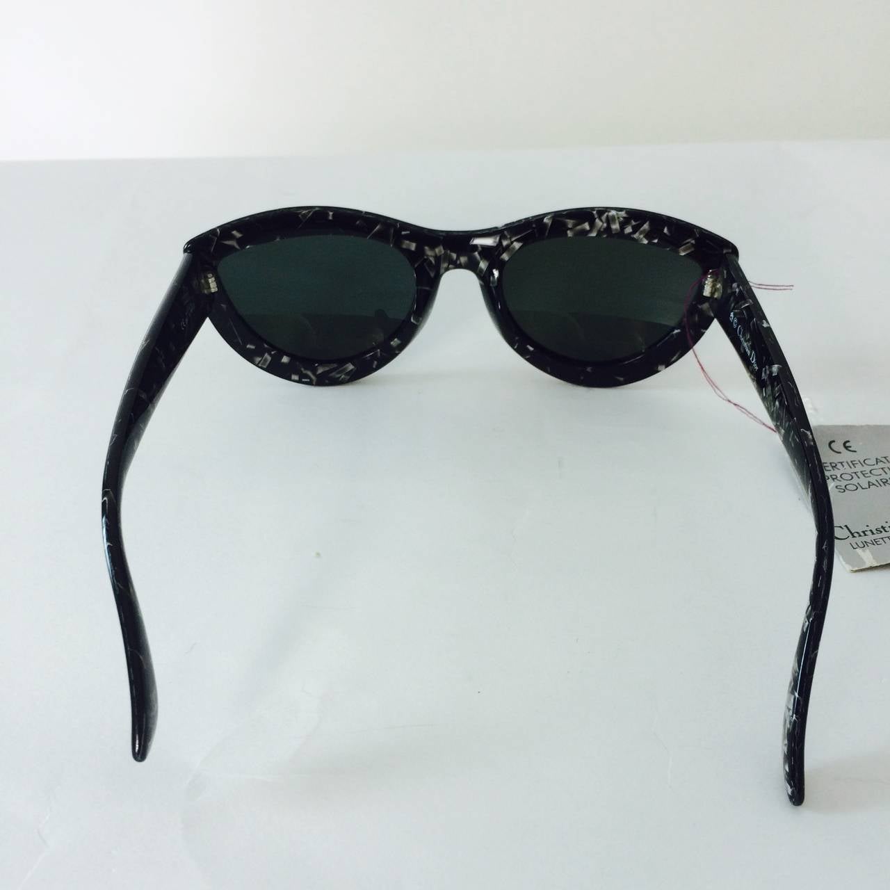Christian Dior Lunettes De Soleil sunglasses from the 1970s never worn with the original tags...Black frames have geometric bits of grey & white floating through, that create a very mid century look...Modified cat eye frames have original smoke grey