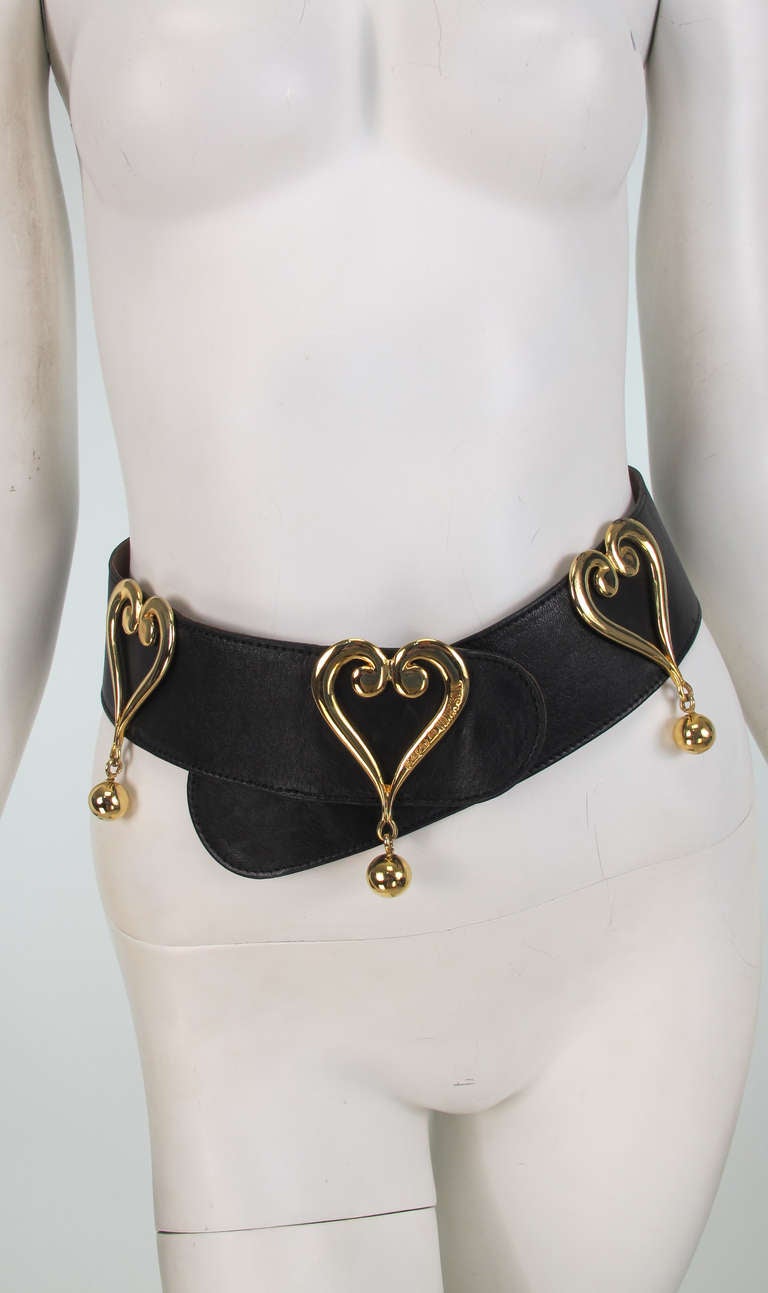 Moschino wide black leather belt with stylized hearts in gold metal, the bottom of each heart has a dangling gold ball...Fits a modern small...