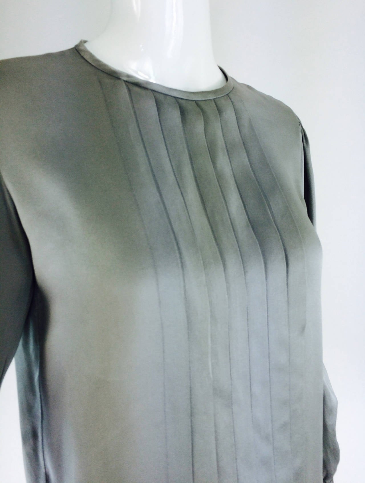 1970s Yves St Laurent silver grey silk satin pleat front blouse...Round neck blouse closes at the back with a single button and loop, long sleeves with button cuffs, pleats at front...Marked size 34...

Please check the measurements provided below