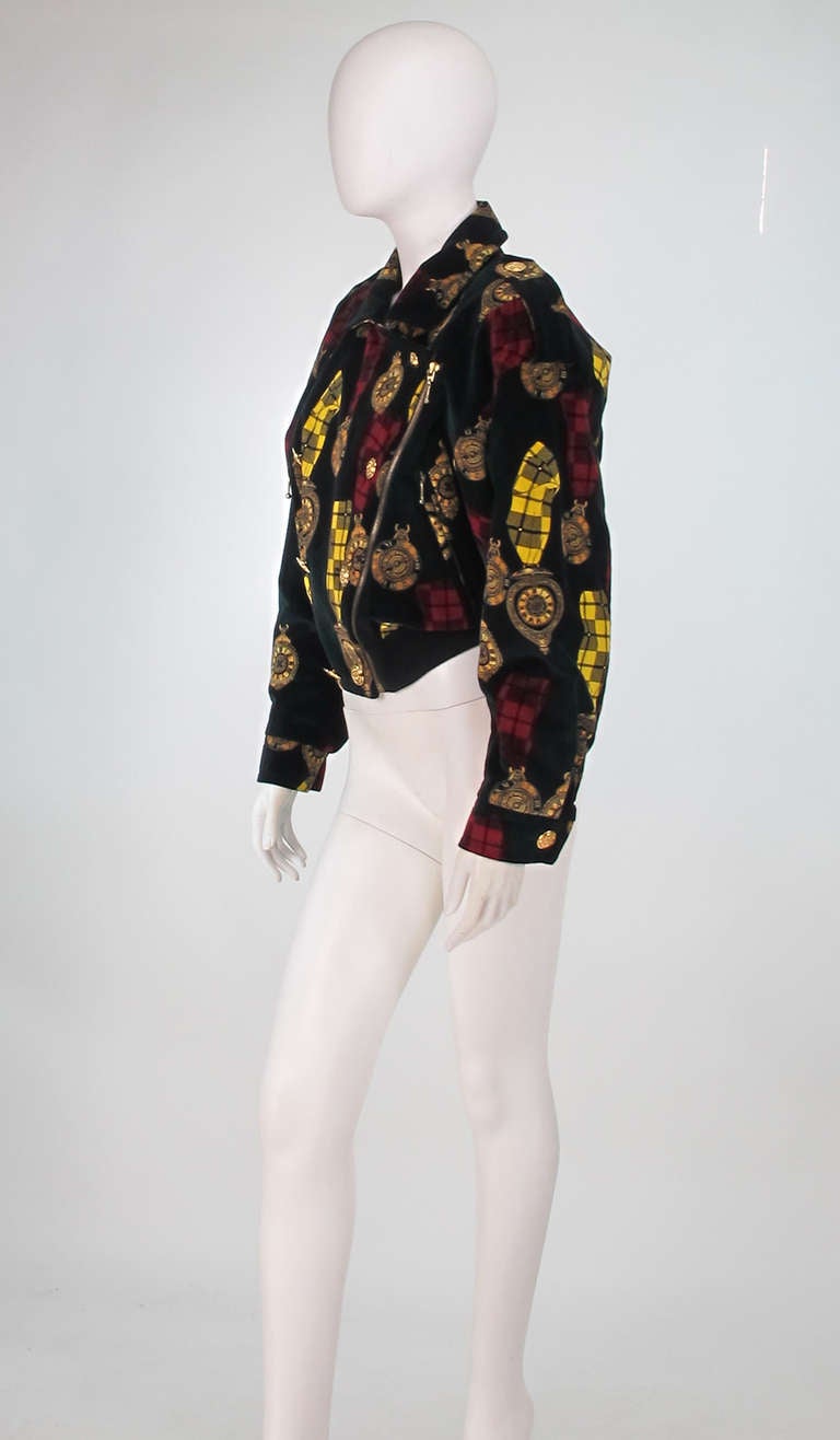 Escada clock printed velvet bomber jacket from the early 1990s...Soft cotton velvet in black with print of watches on plaid ribbons...Jacket has dropped shoulders and epaulets with gold buttons...Jacket closes at the front side with gold buttons and