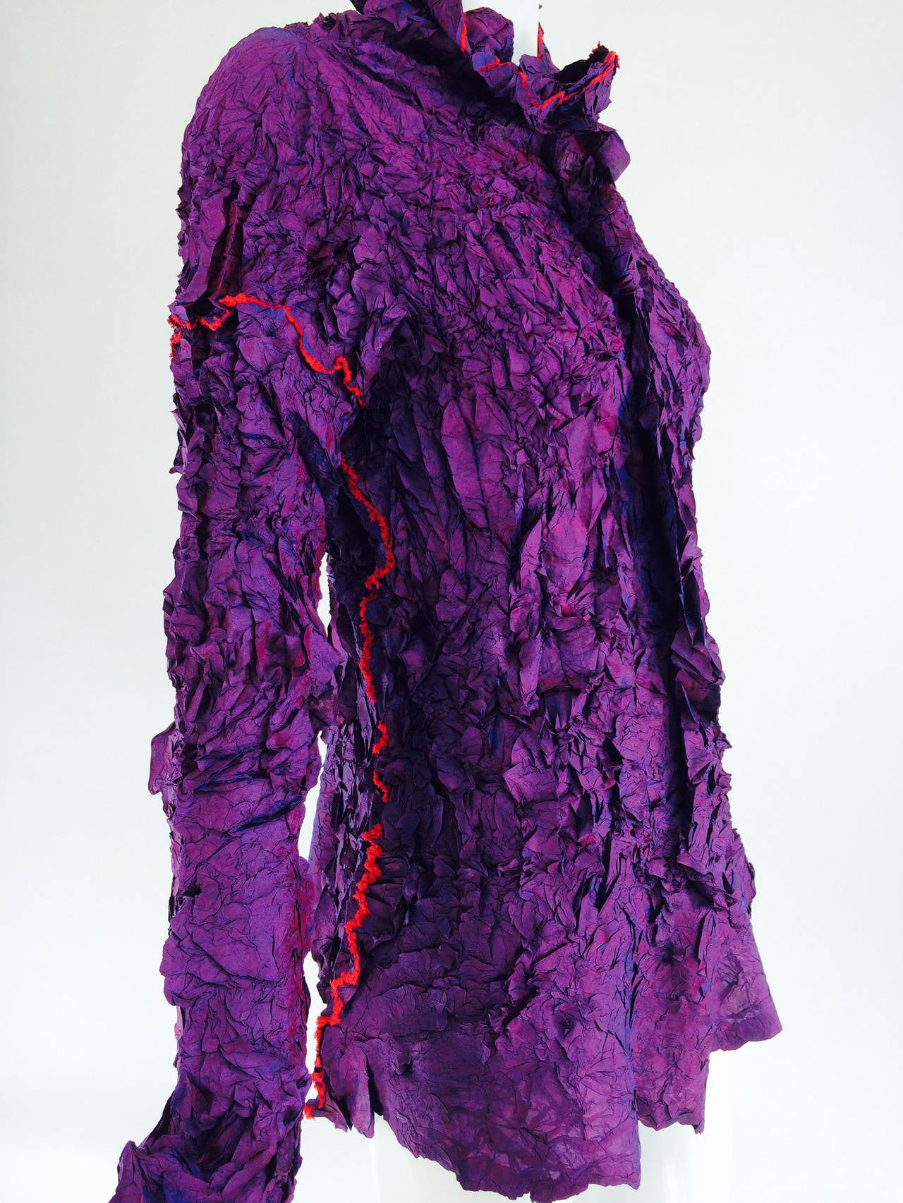 Issey Miyake shibori/compressed fabric pull on top in gorgeous tones of purple/red/silver/copper depending on the light...The top has a mock neck and extra long sleeves...There is a vertical flange seam at the center front about the neck to the