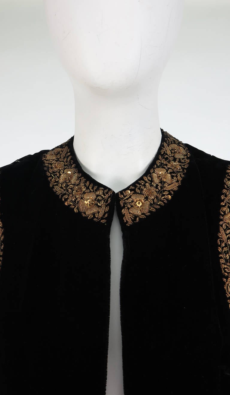 Silky black velvet vest from 1960s India, labeled Bazar Boutique, New York...Heavily gold bouillon embroidered facings and hem feature mini peacocks, flowers and foliate images...Single hook/eye closure at the neck front...Fully lined in black