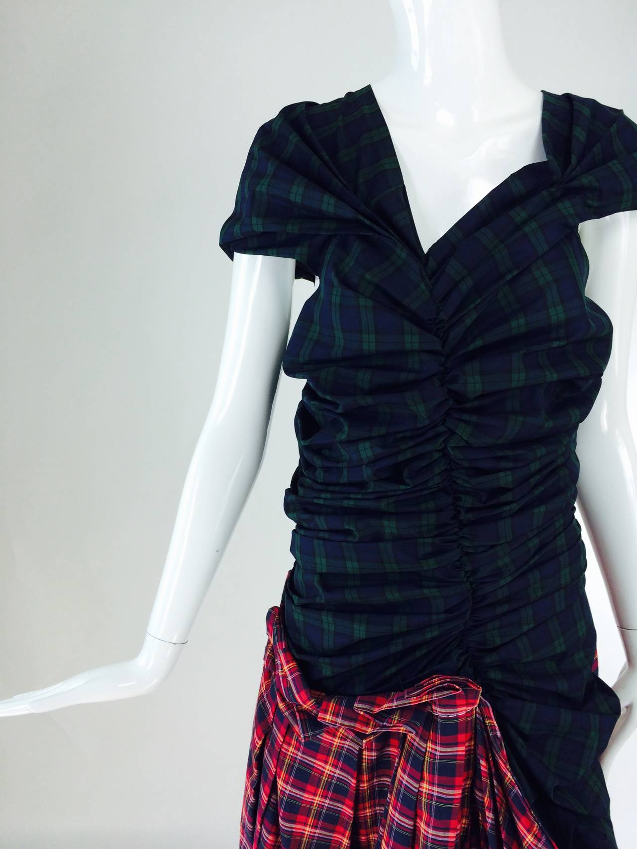 Comme des Garcons tartan/plaid dress in green & red 2005..Short sleeve dress with a shirred bodice of green tartan/plaid...Attached asymmetrical draped skirt of red tartan/plaid...The dress is unlined and closes at the back with an exposed silver