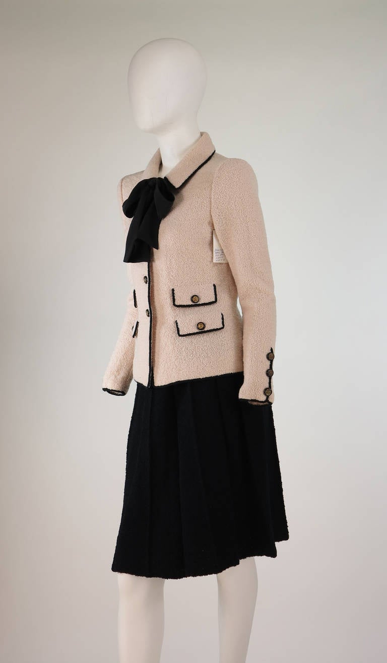 1960s Adolfo classic boucle suit in pink & black...Pale pink jacket is trimmed in black, single button front closure with 4 button flap front pockets...Long sleeves have black trim with gold button detail...Attached black silk tie at the neck front,