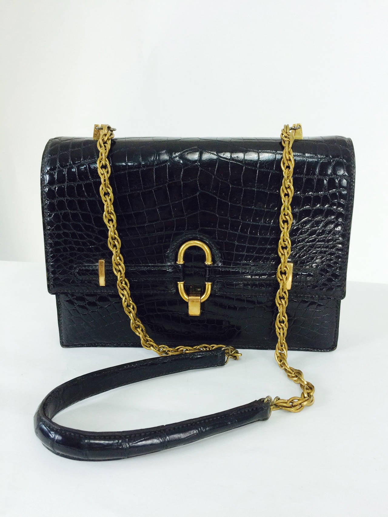 Crocodile shoulder bag with glazed black skins & gold plated hardware purchased in France in the 1970s...Beautiful and well made bag is fully lined in buttery soft black leather...With an unusual chain and crocodile strap...
The interior has a